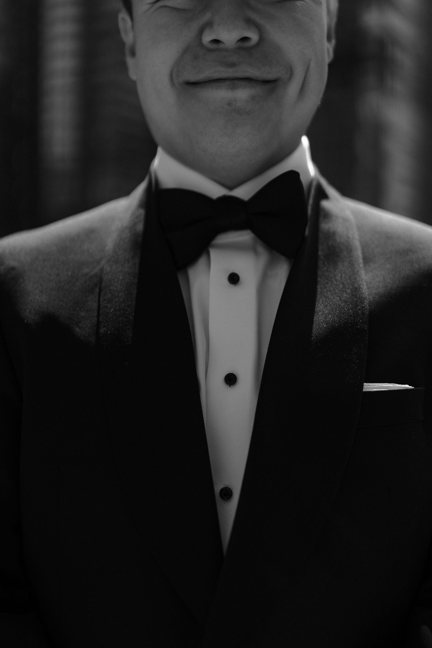 Black and white close-up of formal attire showing classic tuxedo with bow tie and studs on white dress shirt.