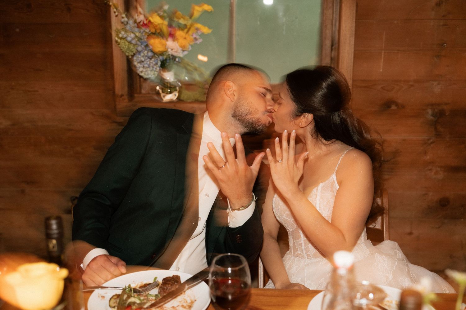 Couples share intimate moments at a rustic barn wedding reception with warm lighting and wooden decor.