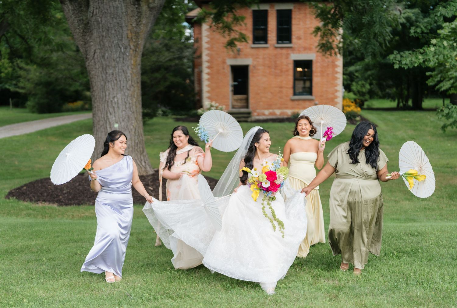 A series of candid wedding party photos showing joyful moments on a grassy lawn near a brick building.