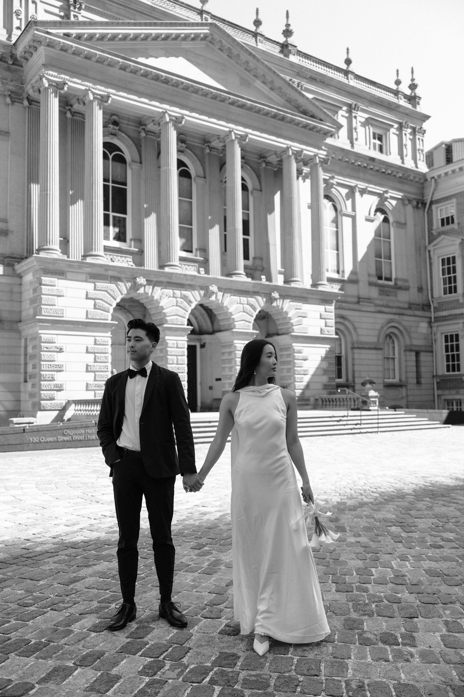 A series of four monochrome wedding photos taken at a grand historic building with classical columns and cobblestone courtyard.