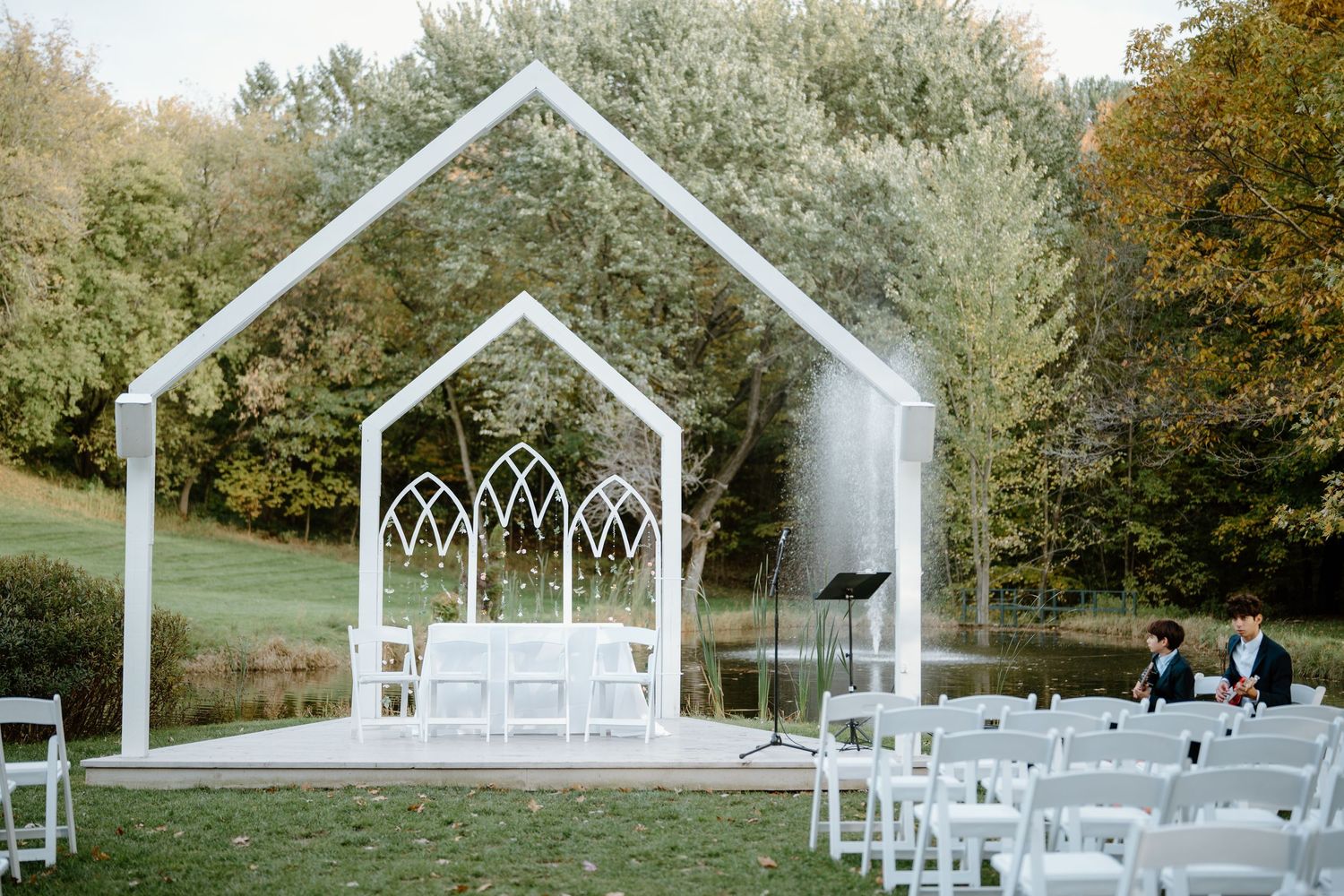 Modern white chapel structure with gothic arch windows set up for an outdoor wedding ceremony.