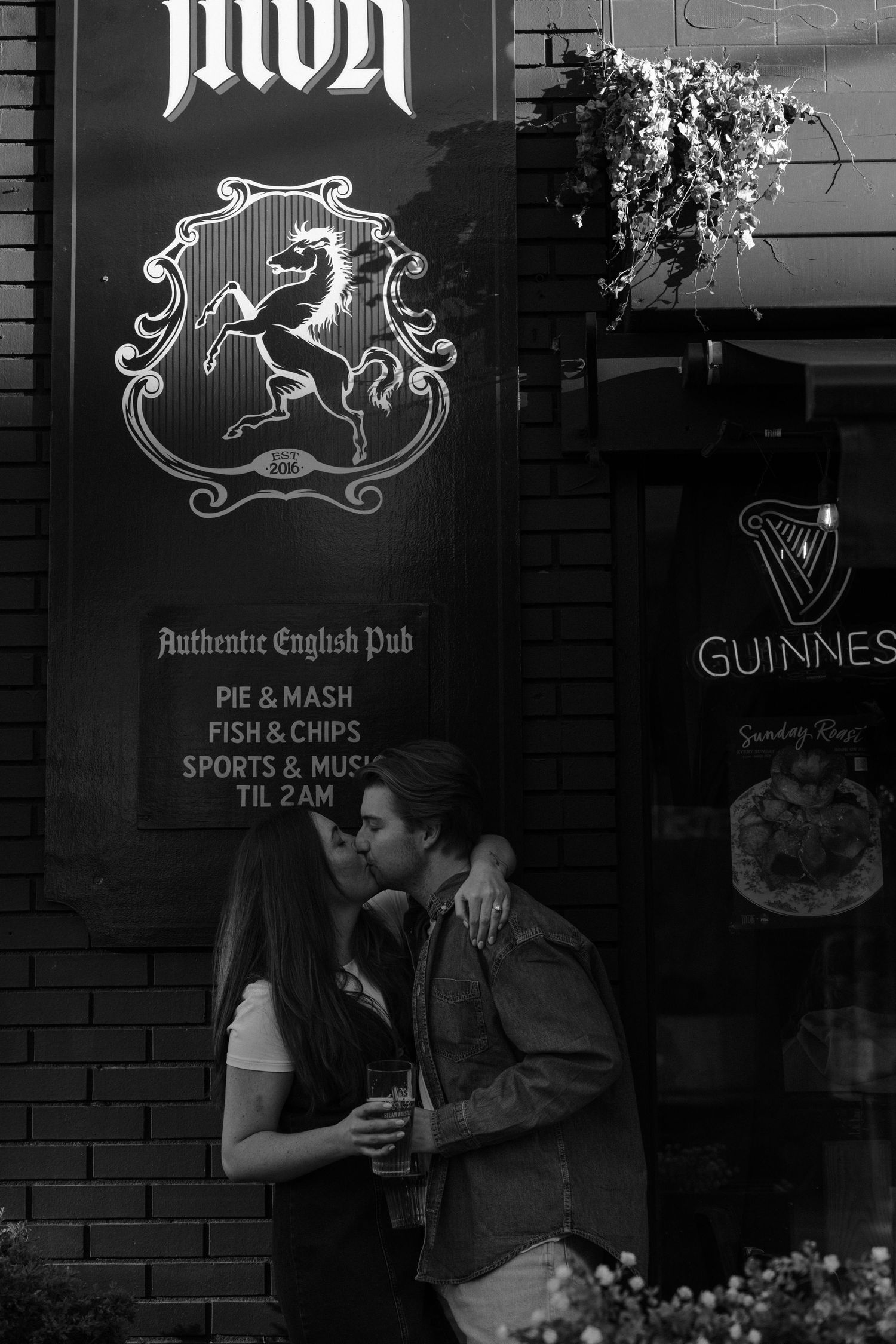 A romantic black and white scene outside an authentic English pub with a heraldic lion crest and Guinness sign.