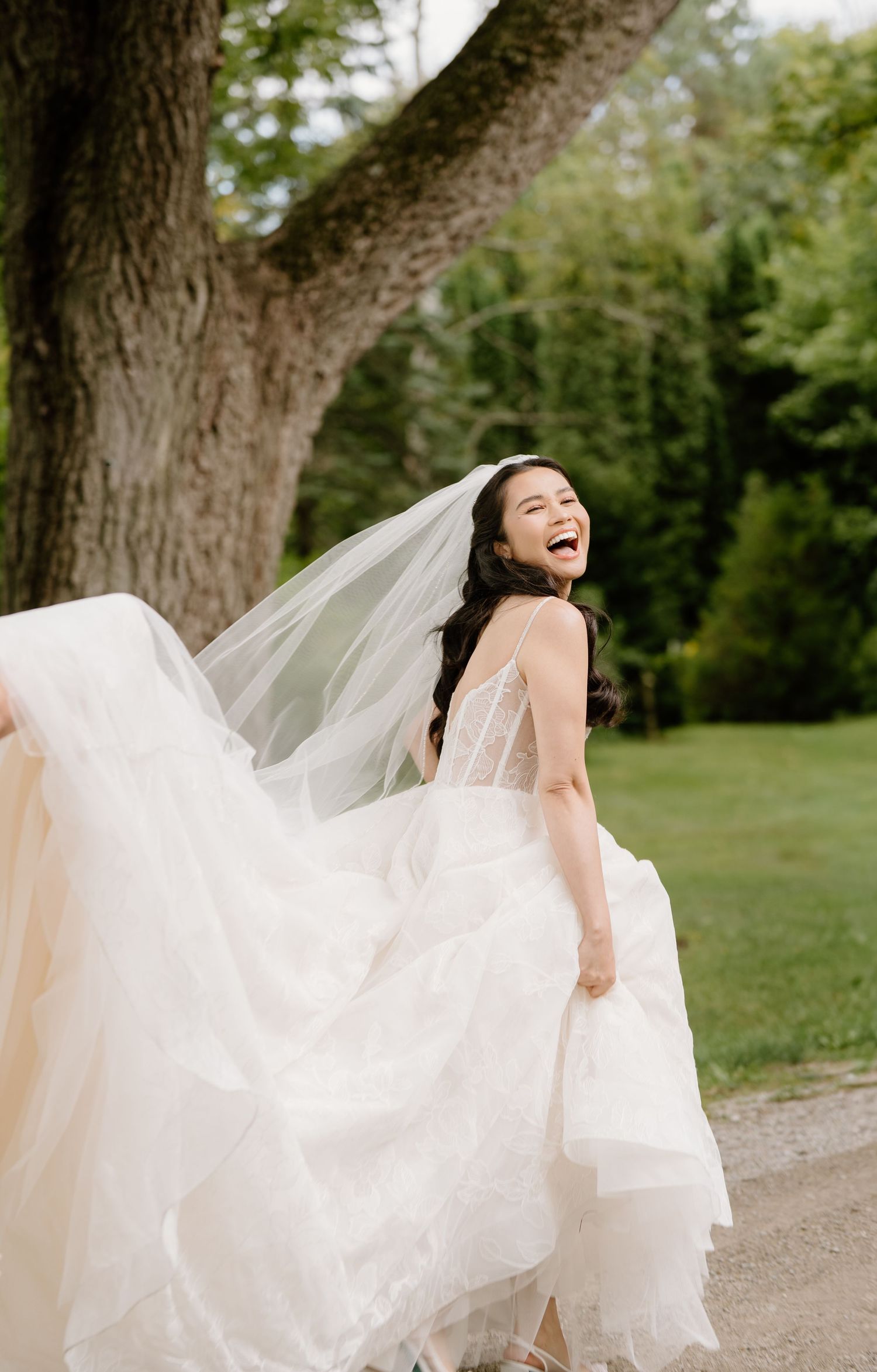 A flowing white wedding dress billows in the breeze on a garden path.