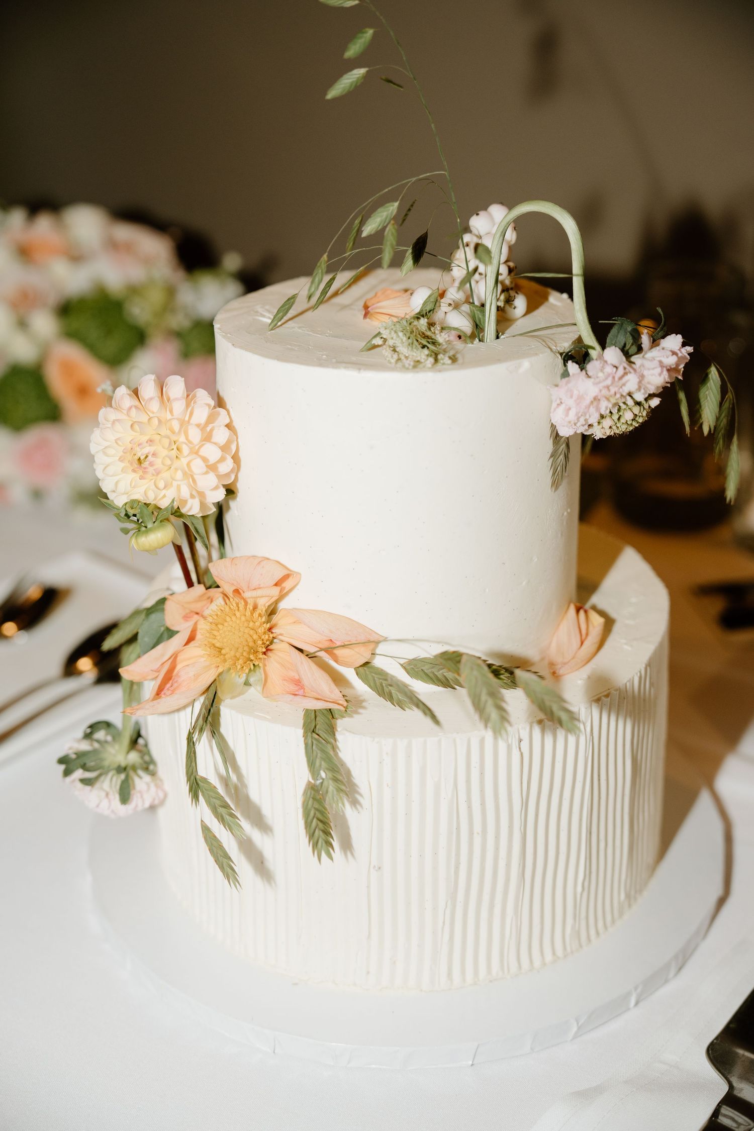 Elegant white textured wedding cake adorned with fresh peach flowers and delicate foliage.