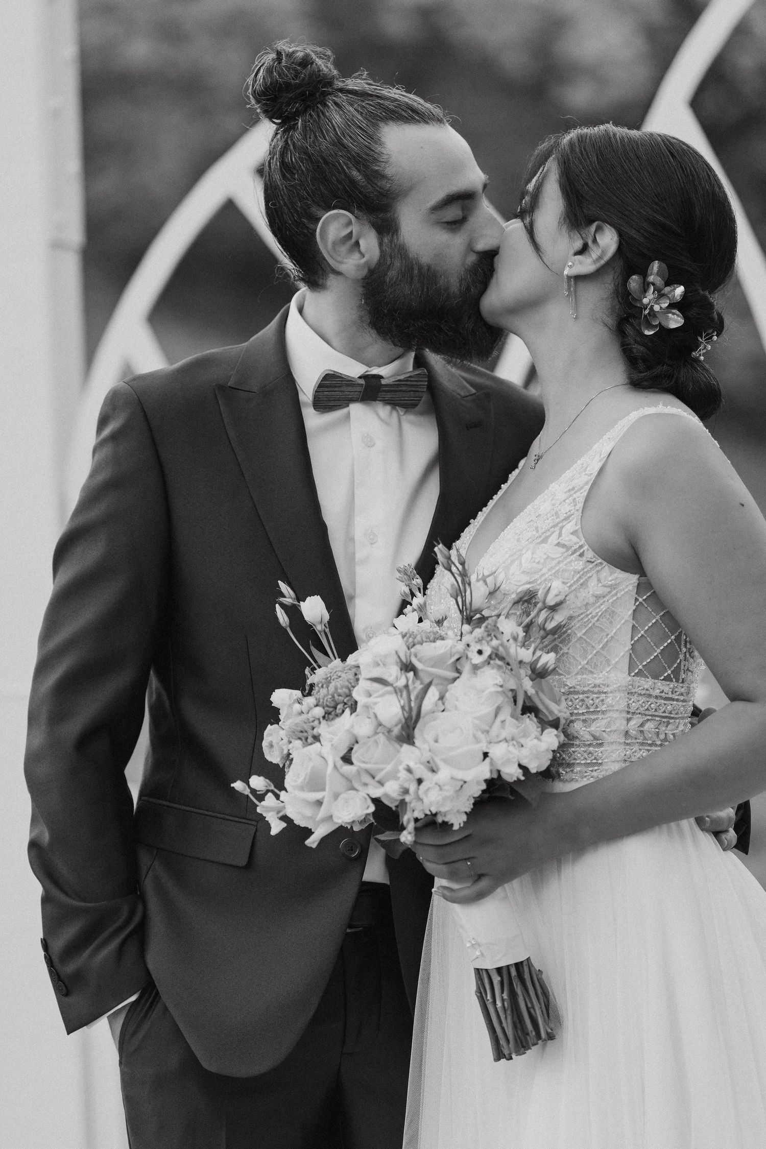 Black and white wedding photo of couple sharing an intimate kiss with elegant formal attire.