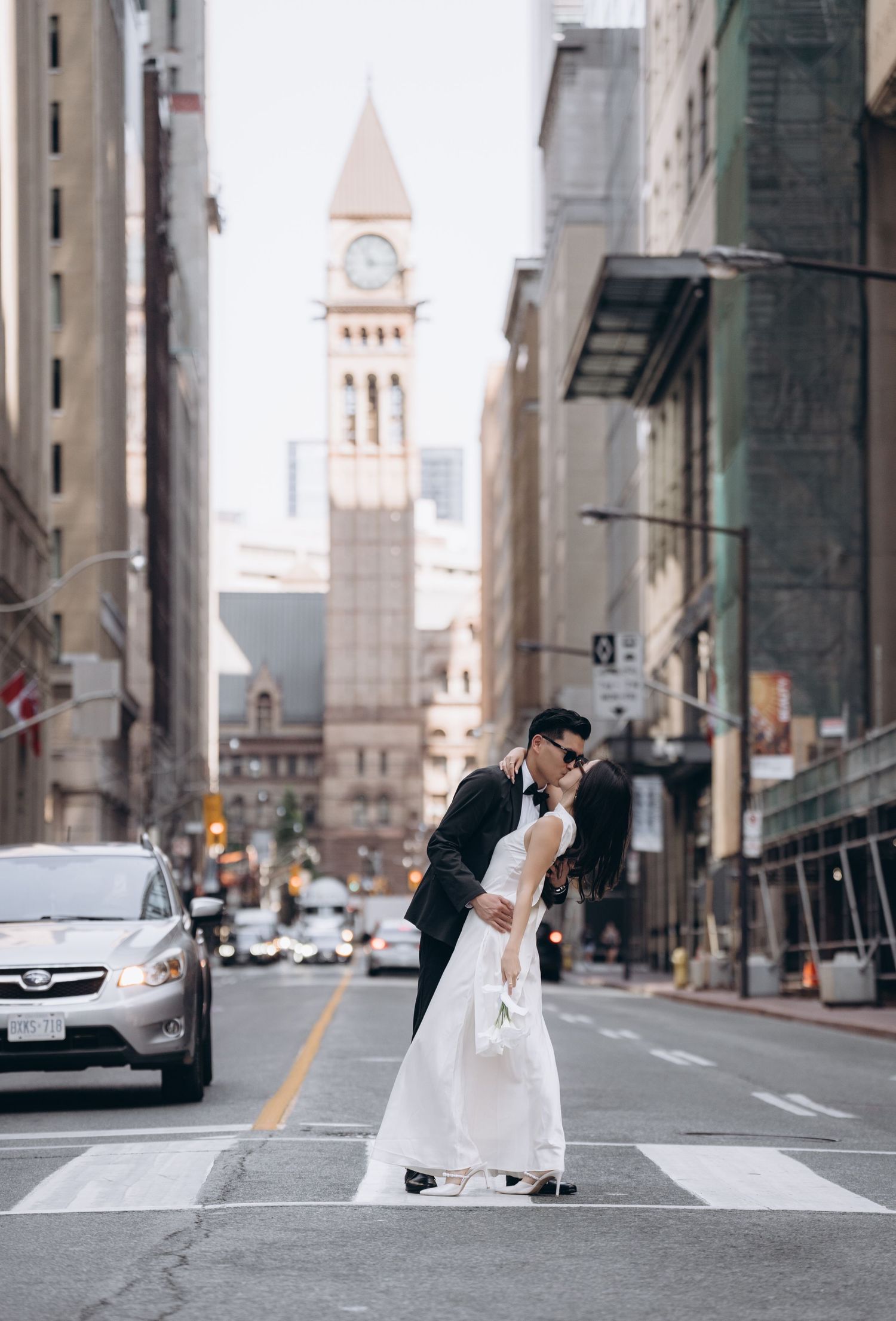 Romantic wedding photo on city street with iconic clock tower visible in background.