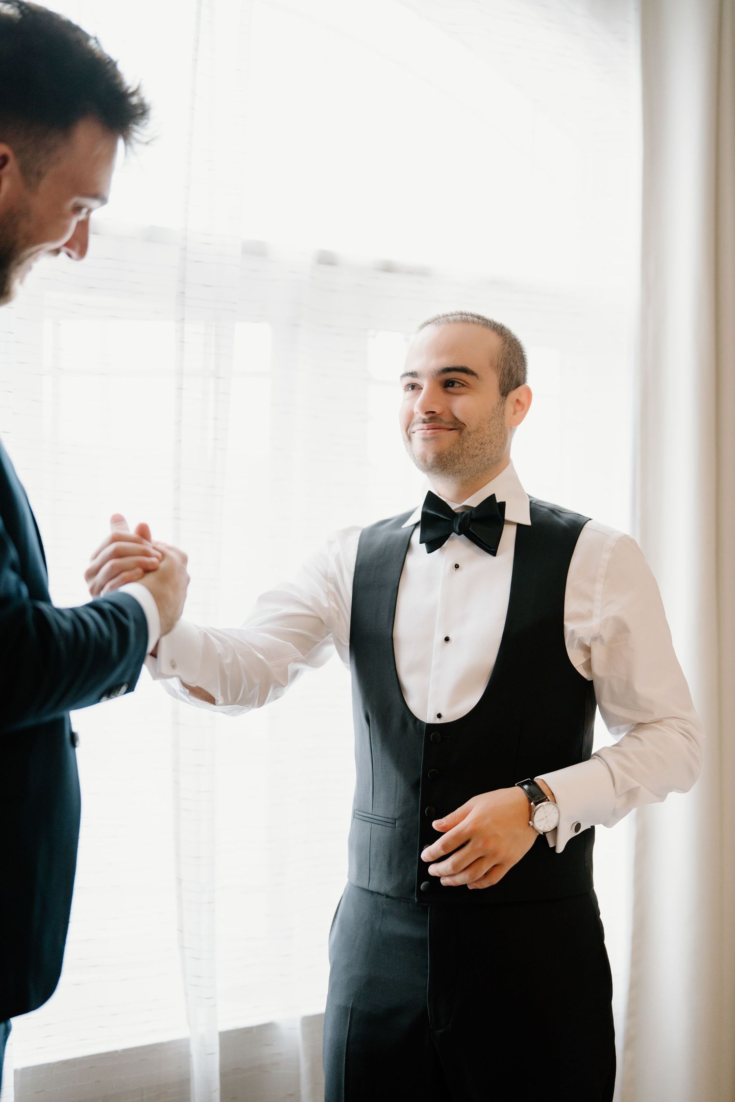 A series of candid moments showing a groom getting ready in formal attire with a black vest and white shirt.