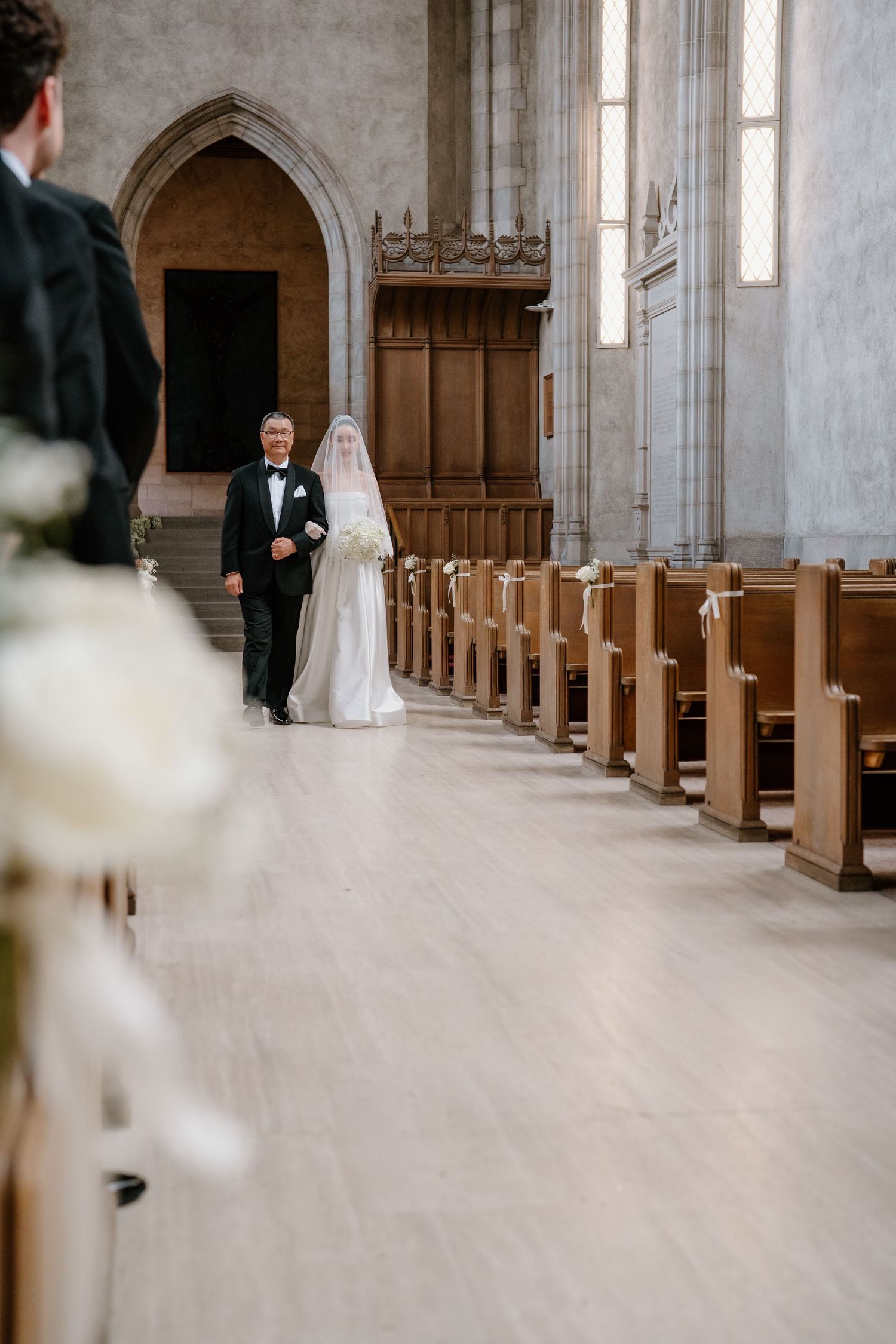 Stone church interior with gothic arches and wooden pews creates an elegant wedding ceremony backdrop.