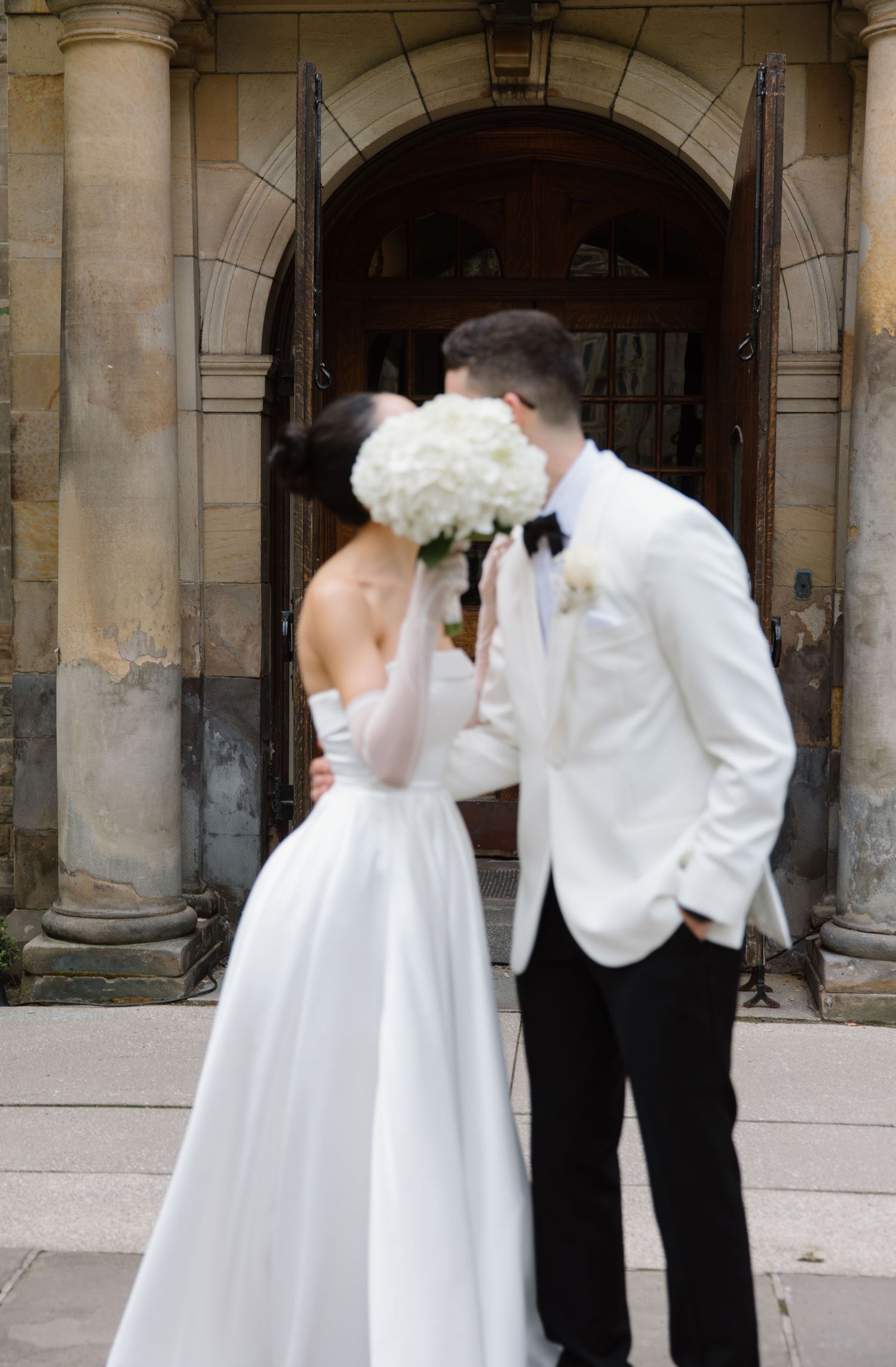 A bride and groom share their first dance in an elegant stone archway setting during their wedding ceremony.