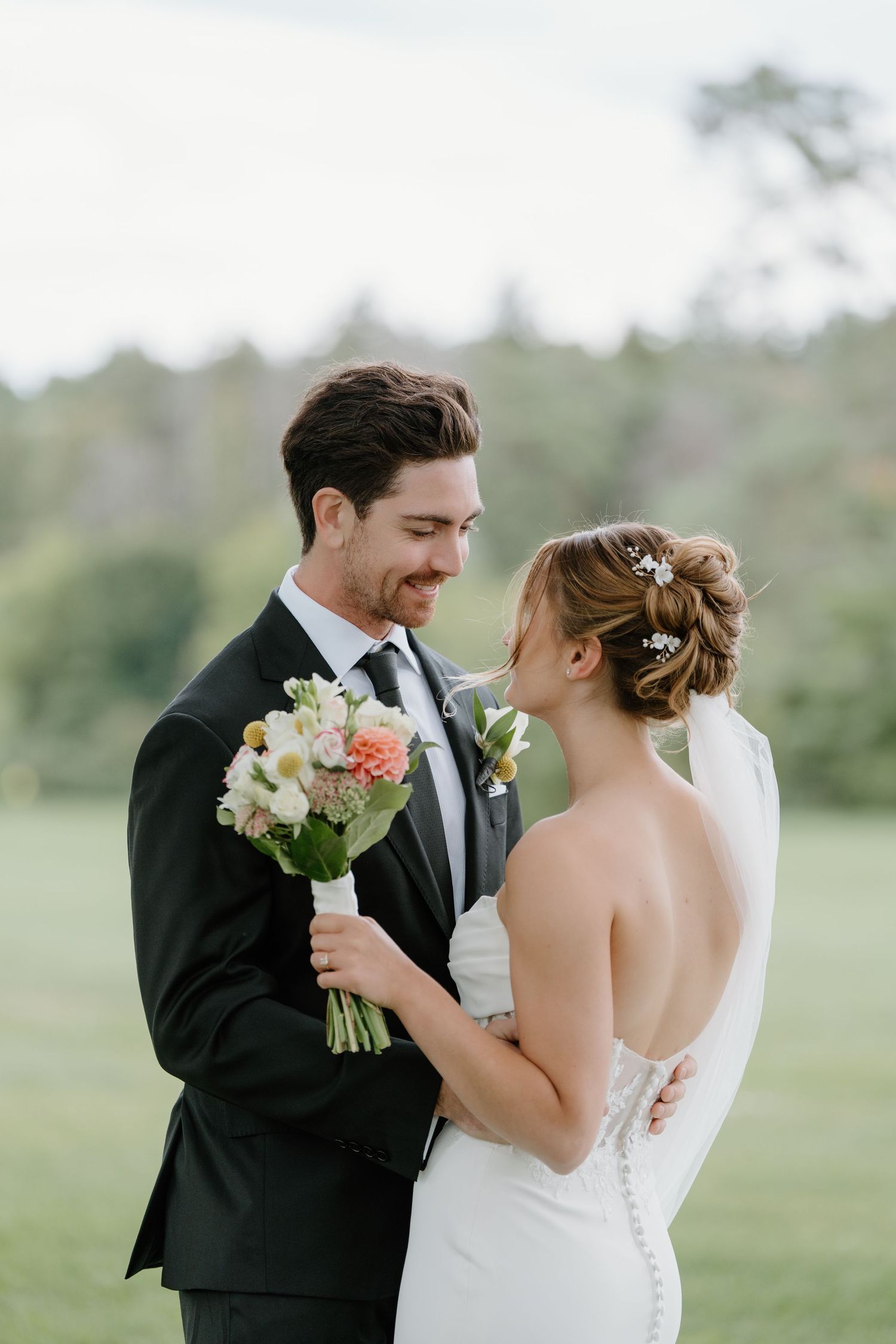 A couple in wedding attire share intimate moments in an outdoor garden setting with soft natural lighting.
