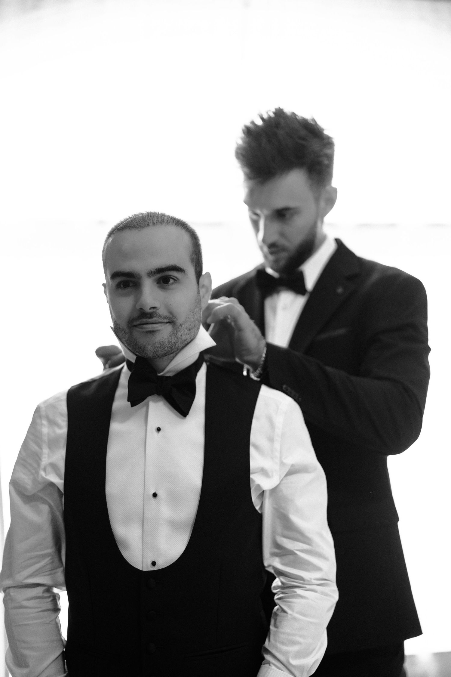 Men in formal black and white tuxedo attire getting ready for an elegant event.