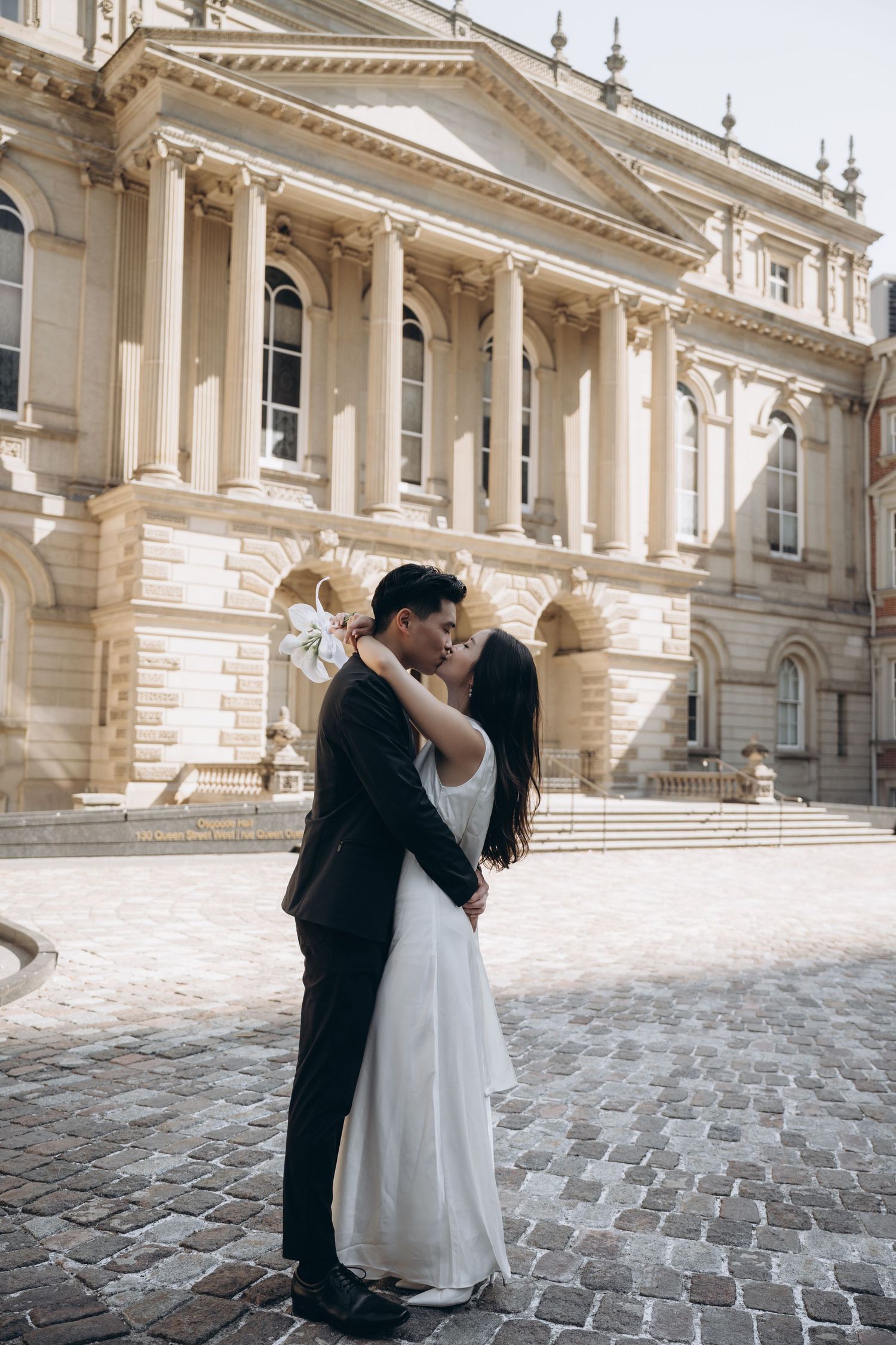 A romantic wedding moment captured in front of a majestic classical building with white columns.