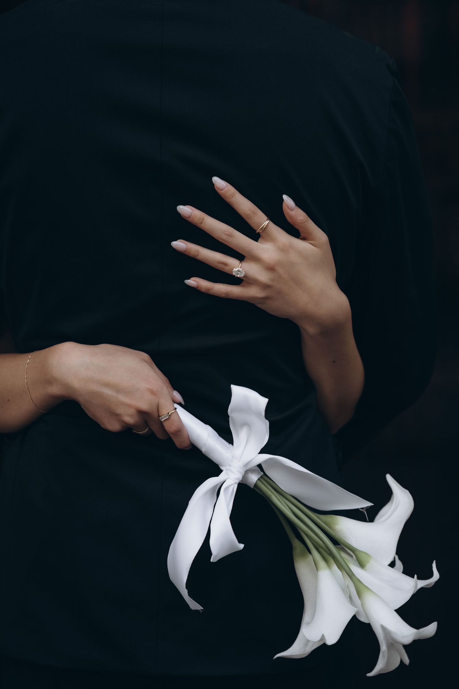 A hand reaches into dark space to hold a delicate white lily flower against a black background in a sequence of images.