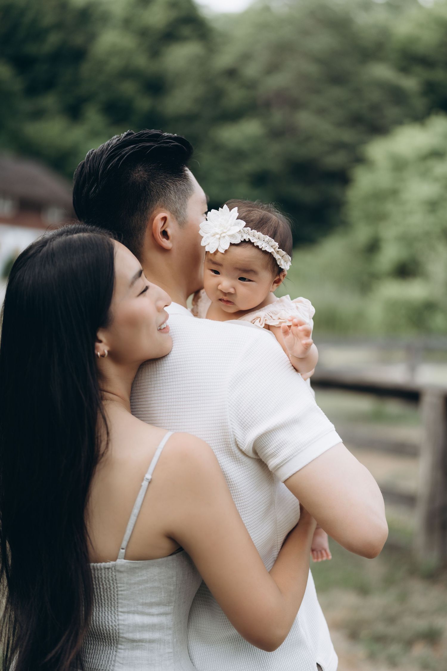Sweet bonding moment outdoors with mother and infant wearing matching white clothes.
