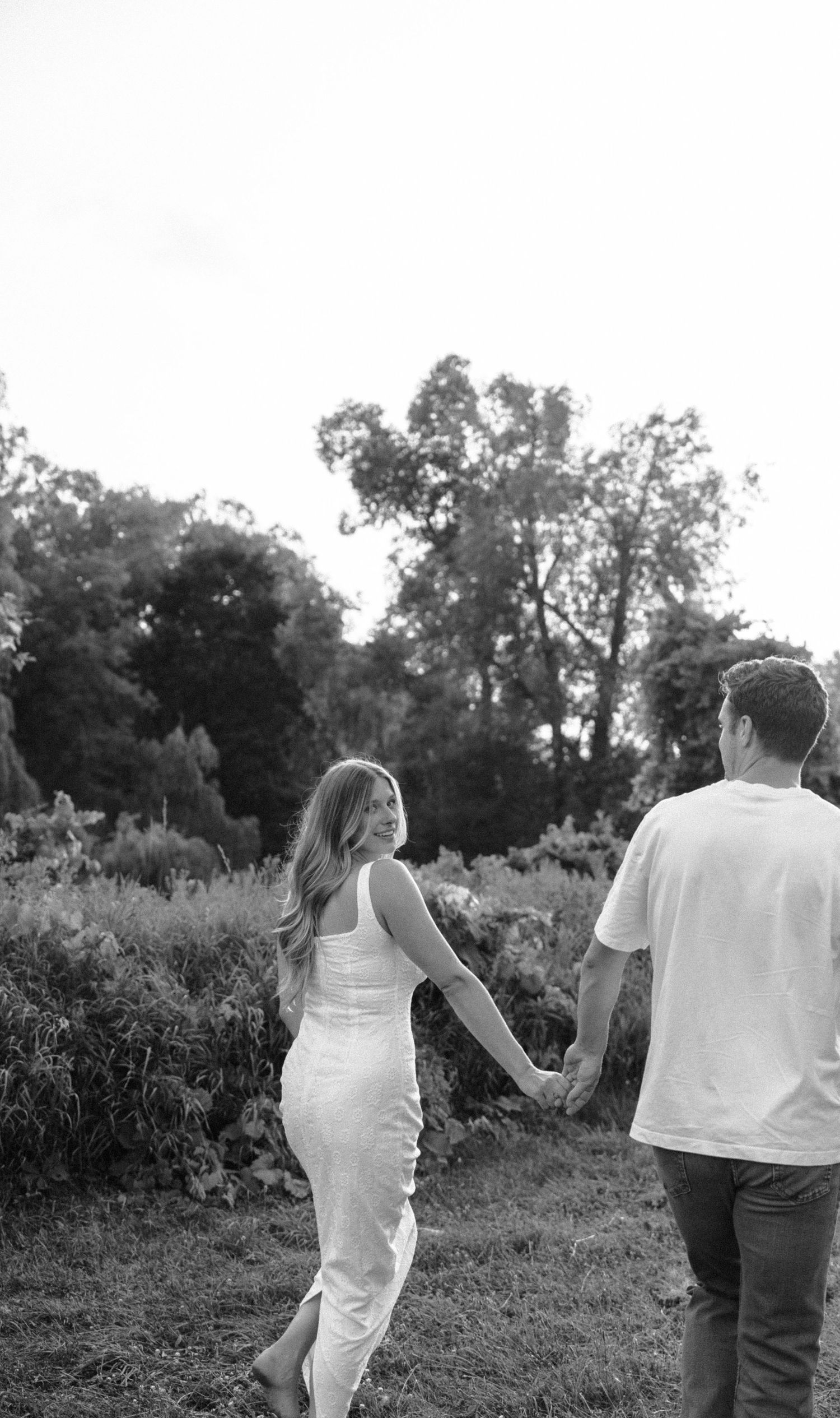 A black and white photo series shows a couple walking through a natural outdoor setting in casual summer attire.