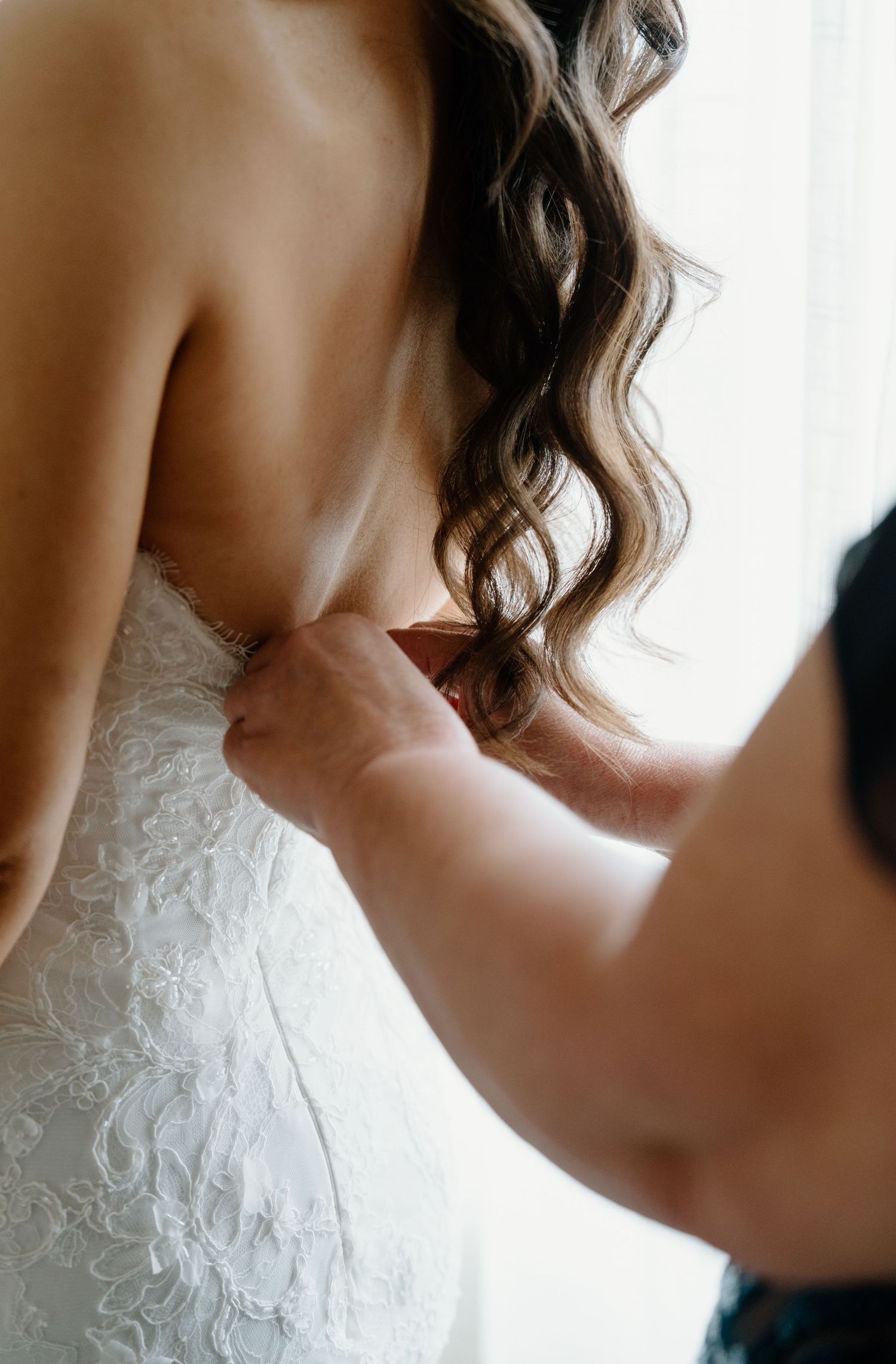 Close-up details of a white lace wedding dress with delicate floral patterns and sweetheart neckline.