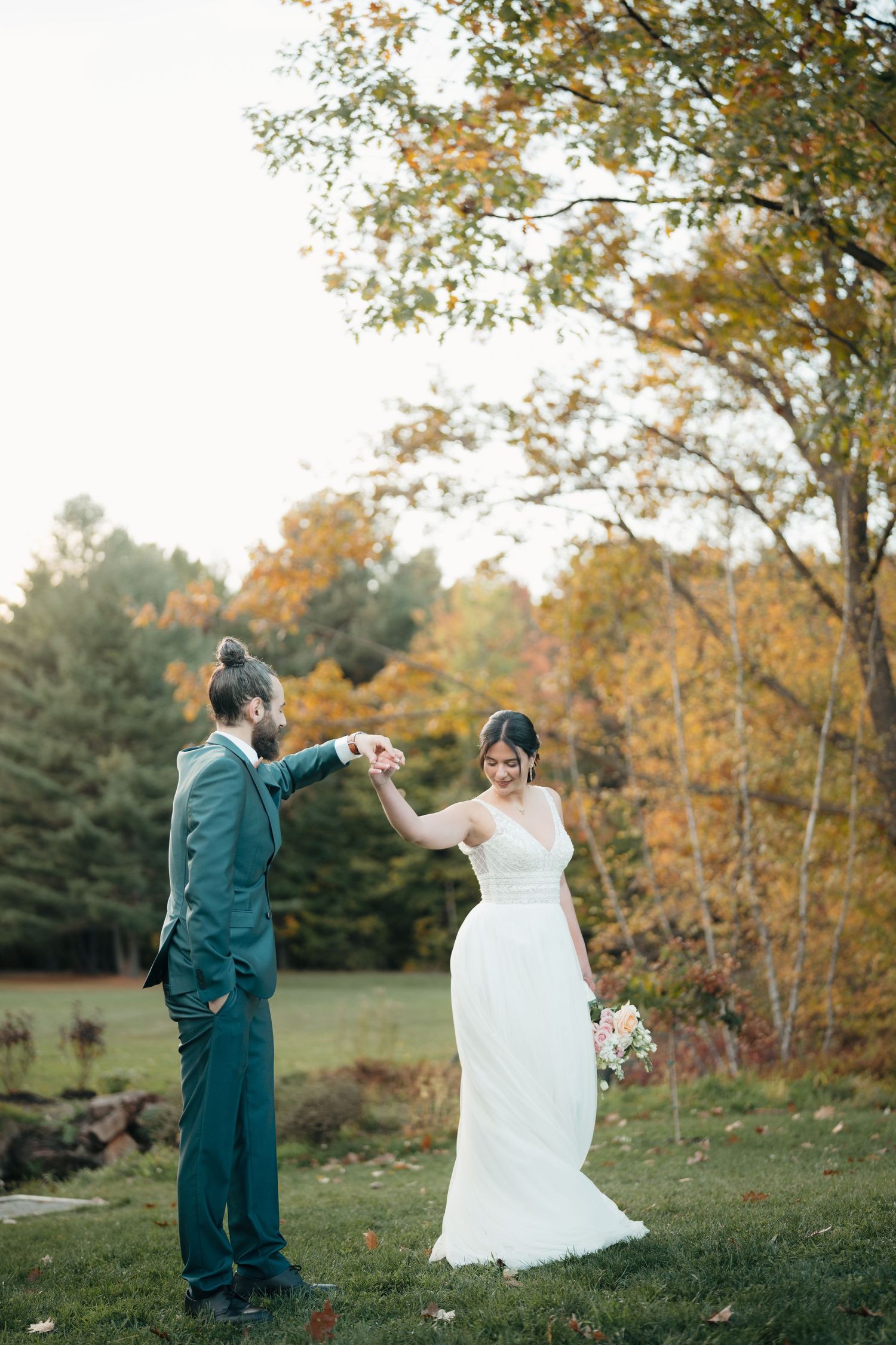 Couple dancing outdoors with autumn trees and foliage in background.