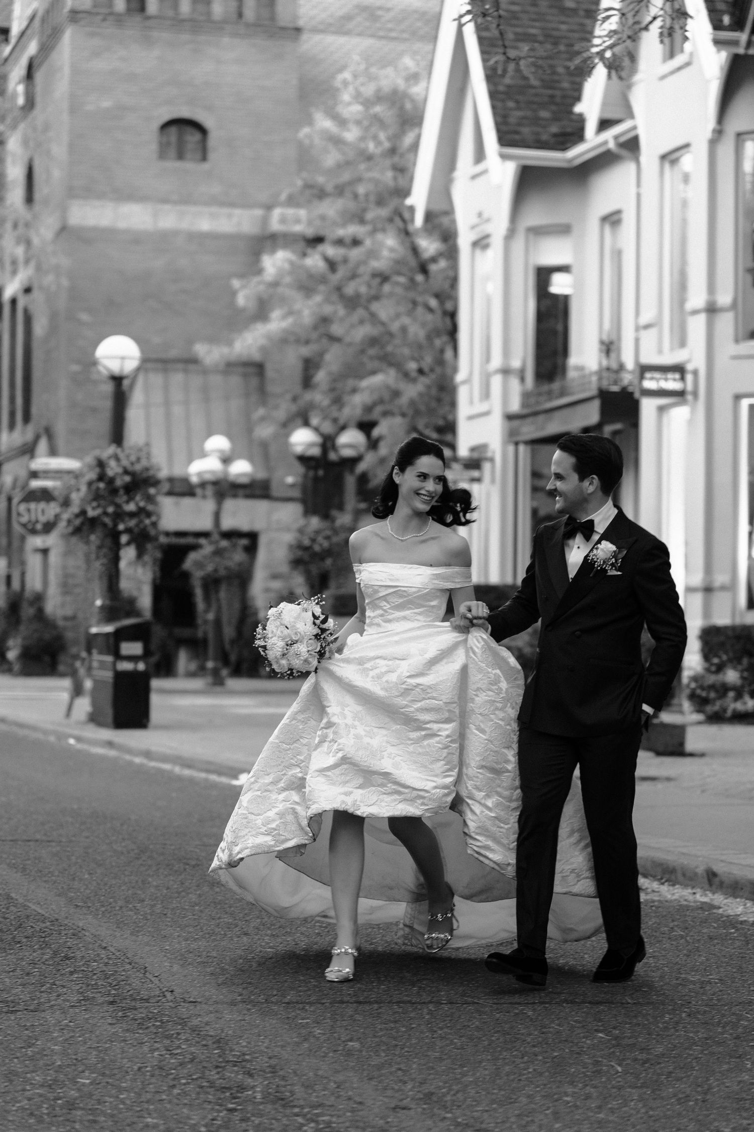 A sequence of black and white wedding photos showing a couple dancing and twirling on a cobblestone street.