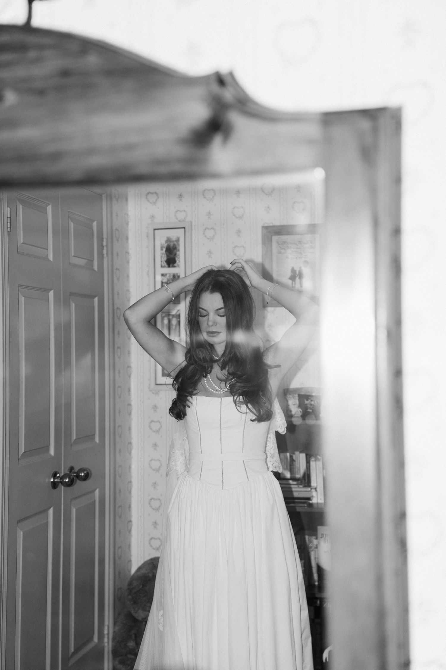 A set of five black and white photographs showing someone in a flowing white dress posing gracefully against a door.