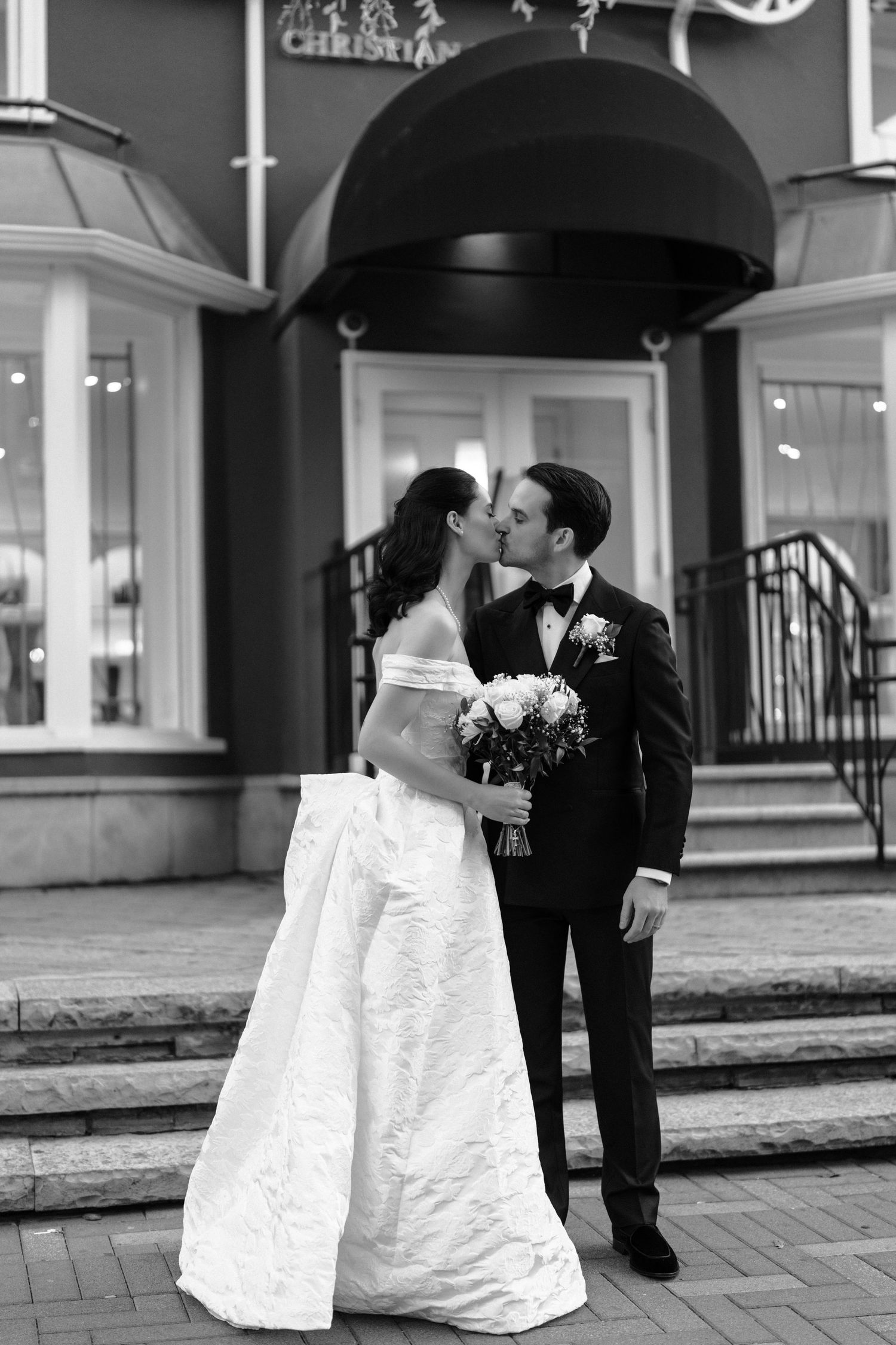 A romantic black and white wedding photo series showing a couple sharing intimate moments under an umbrella.