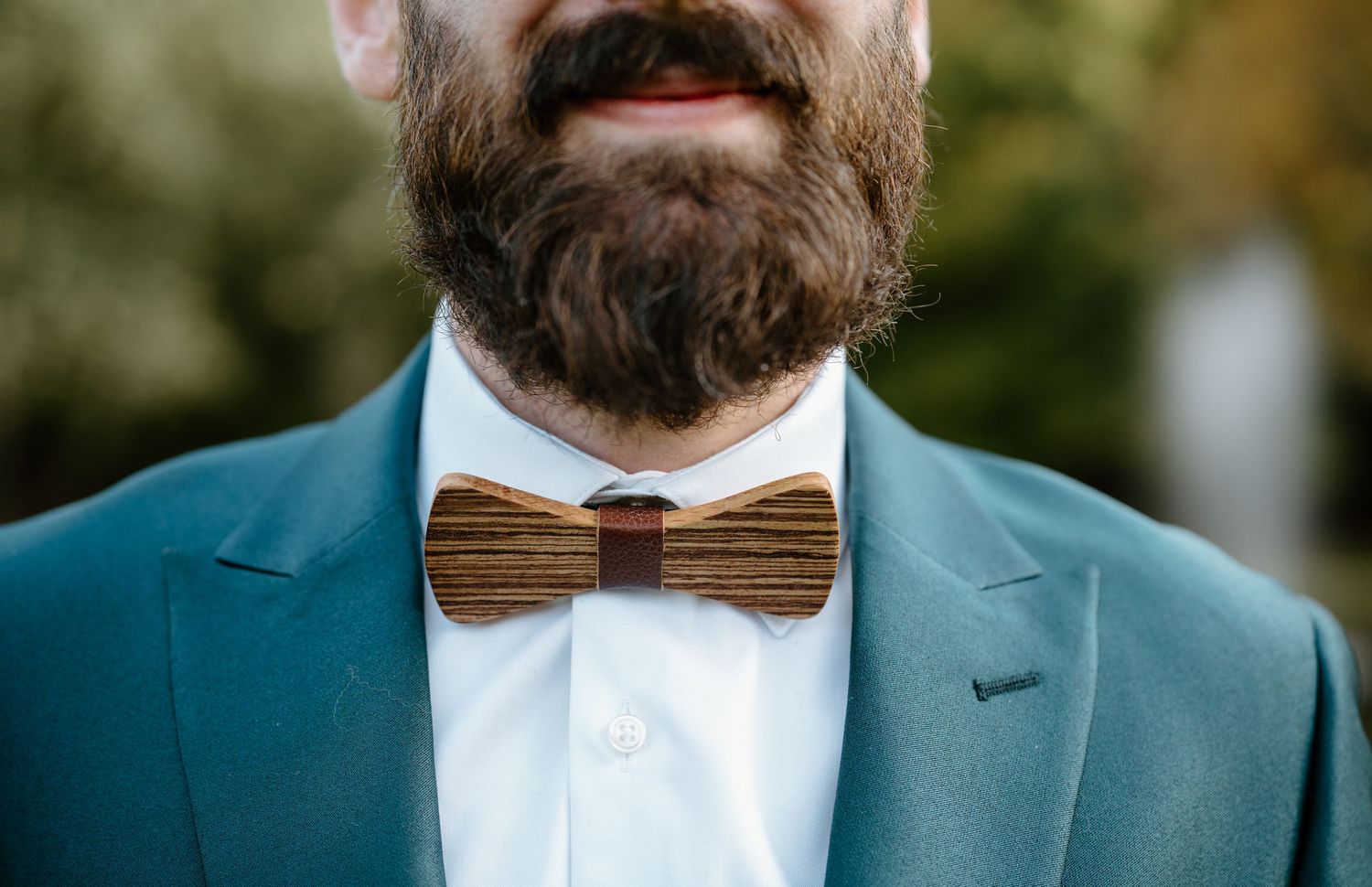 Close-up of wooden bowtie and teal suit jacket showing fine wedding day details.