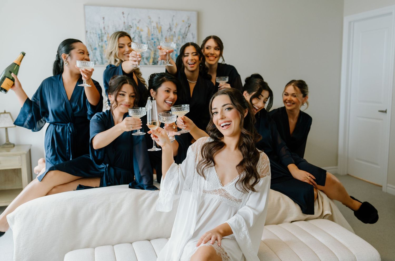 A group in formal attire shares joyful laughter while gathered in a bright white room.