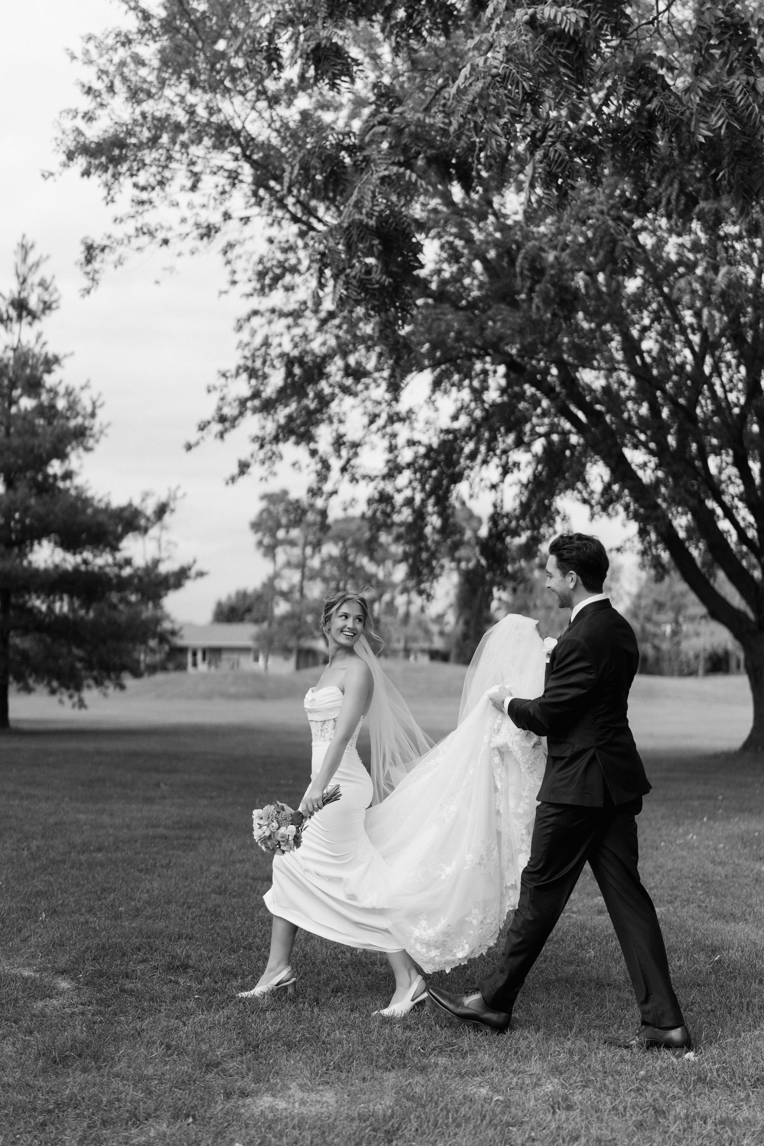 A romantic wedding couple performs a playful dip pose sequence in a grassy outdoor setting.
