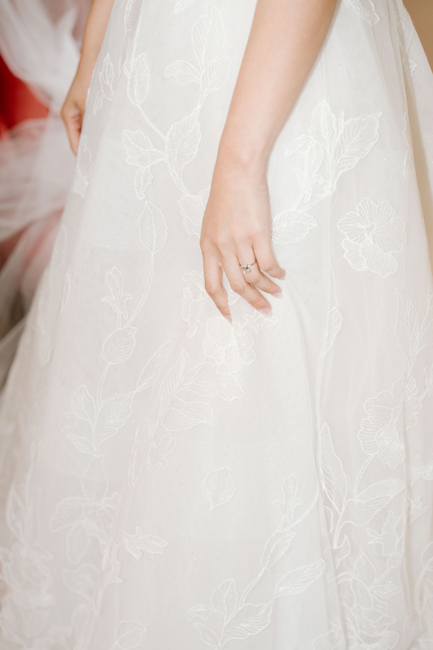 Close-up details of white lace and tulle fabric from a wedding dress showing delicate embroidery patterns.