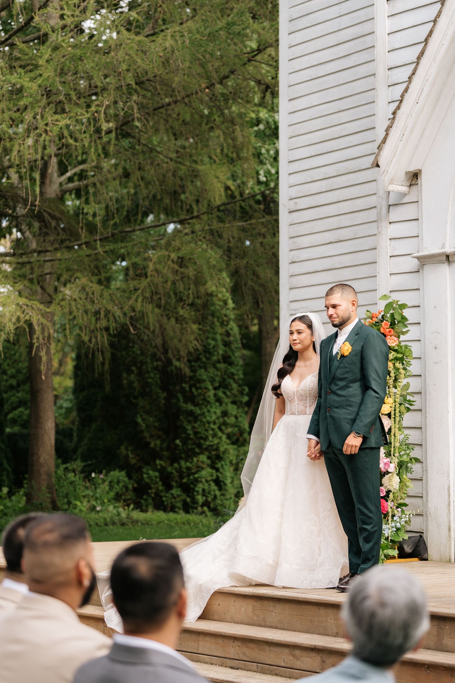A series of wedding photos showing a couple walking together on a deck with trees in the background.