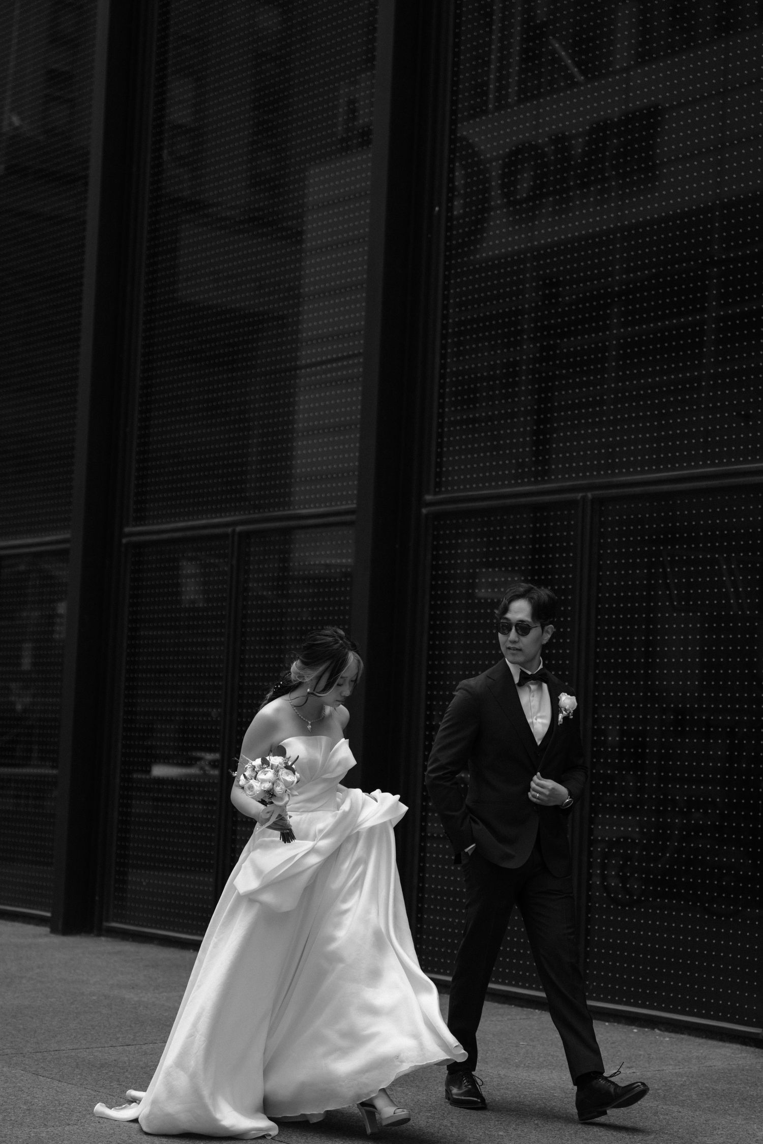 Black and white photography of a wedding couple dancing with flowing white dress movement at an outdoor venue.