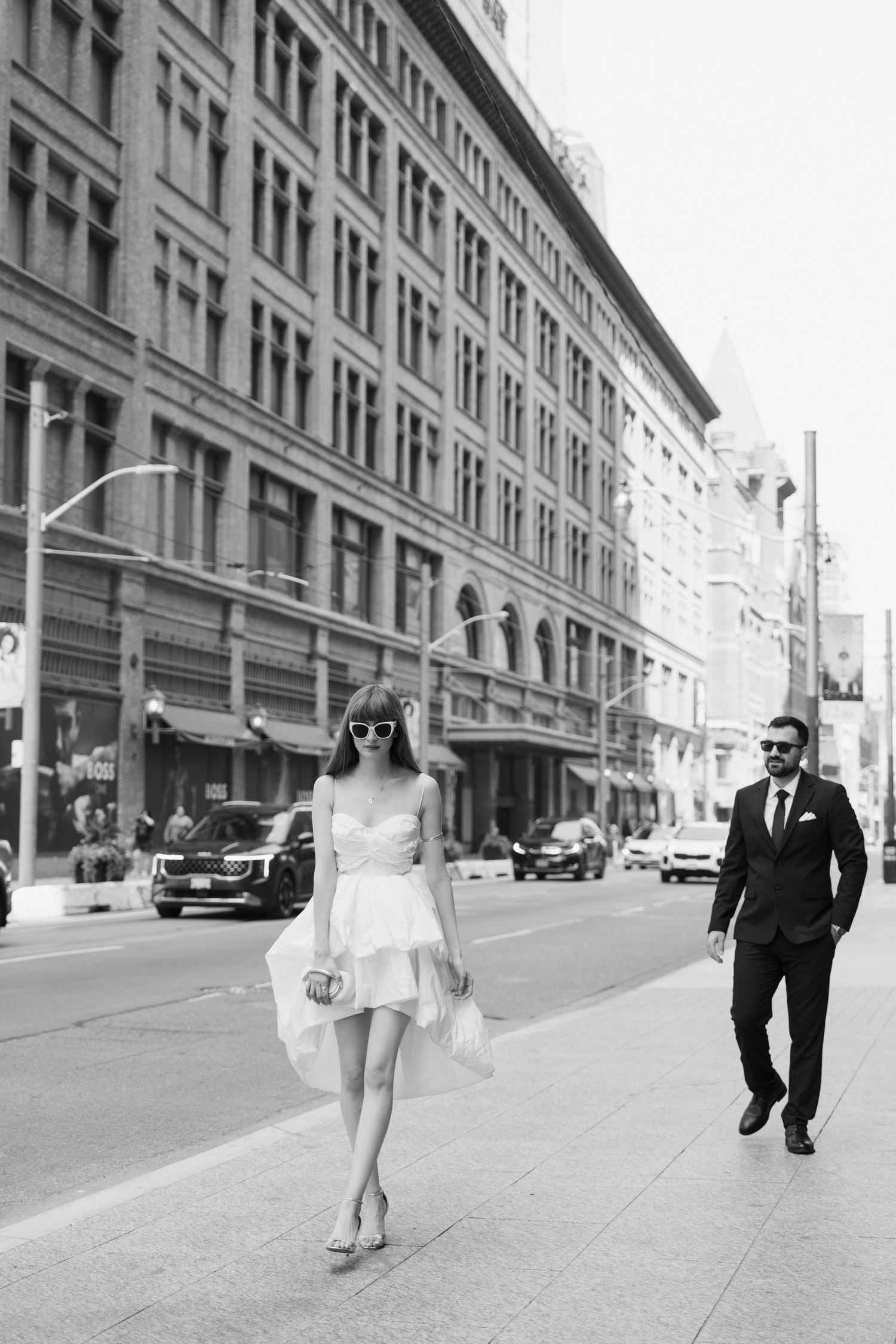 Black and white series of photos depicting figures walking past an urban building's facade on an empty city street.