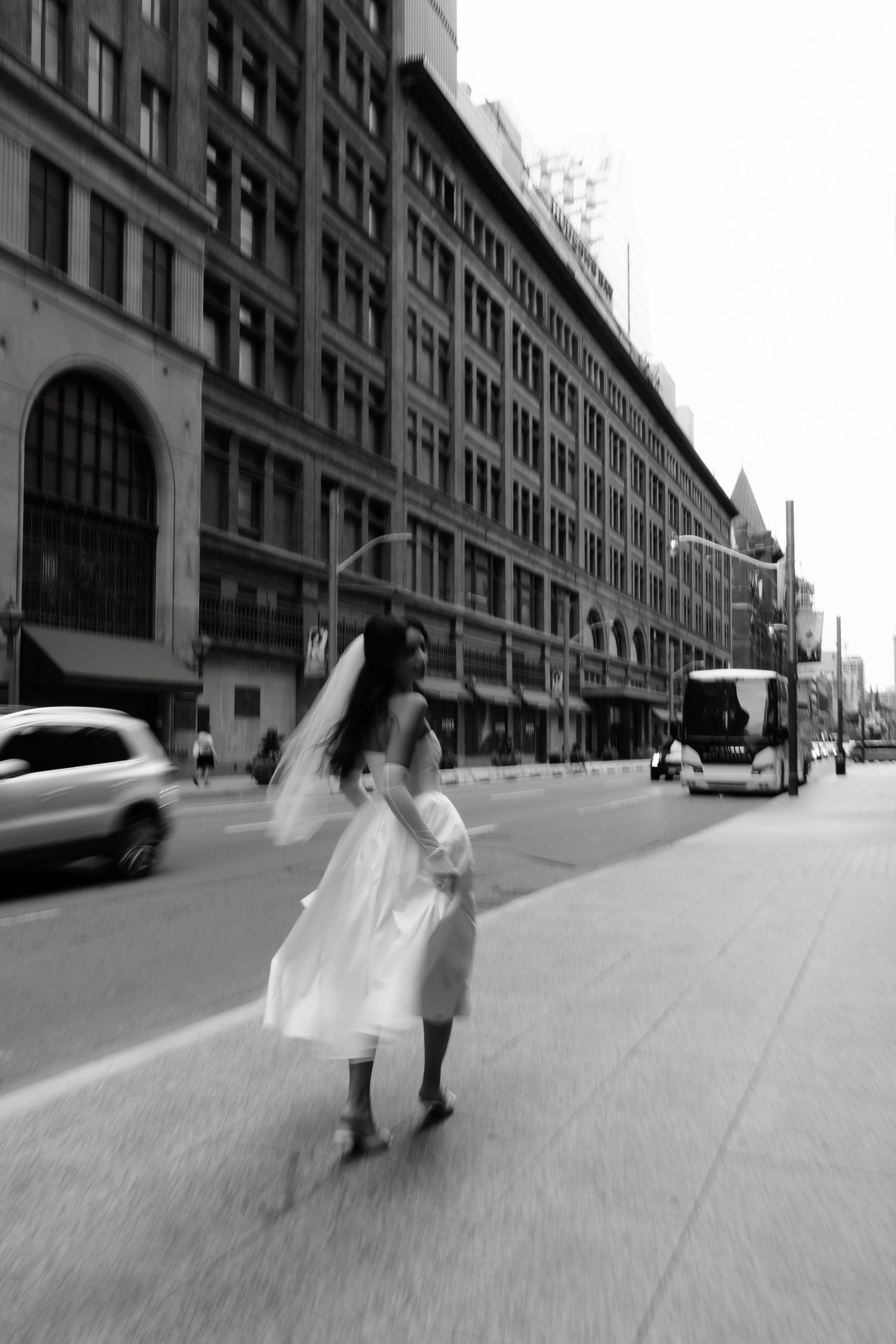 Black and white photo series shows two figures walking down an empty urban street beside a long industrial building.