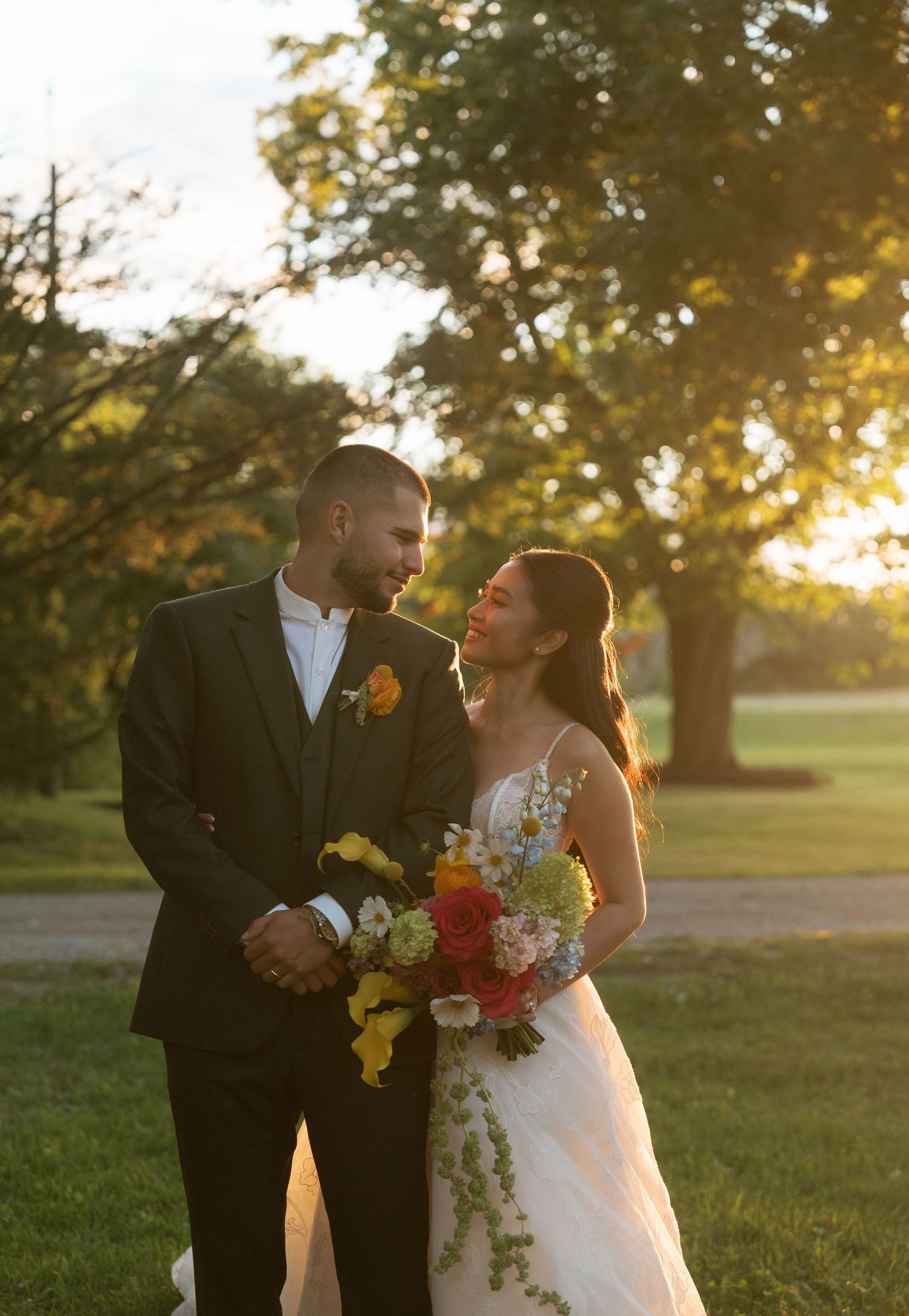 A couple shares a romantic moment during their sunset wedding photoshoot in a grassy field.