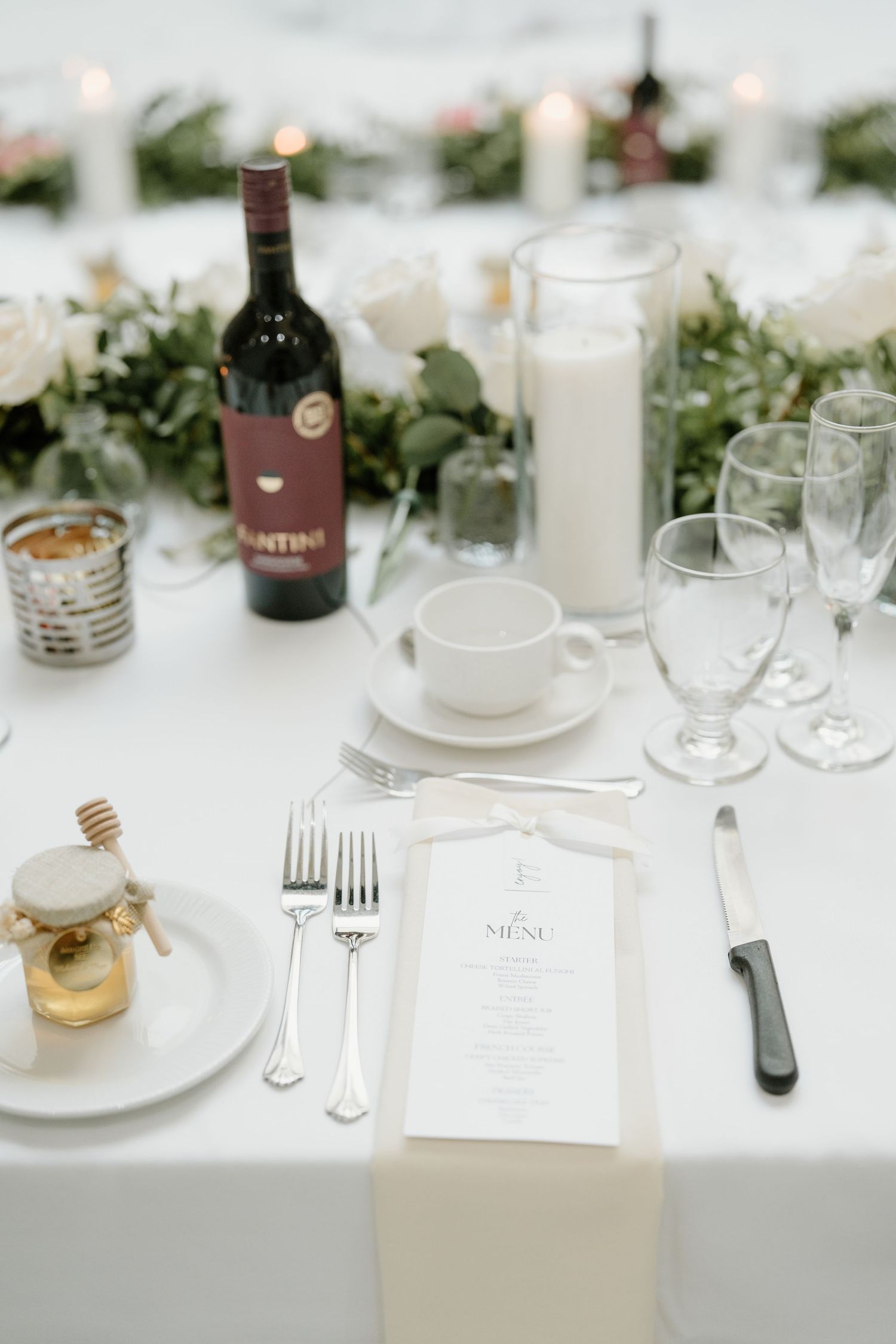 Elegant wedding reception table settings with white linens, candles, and minimalist decor create a sophisticated ambiance.
