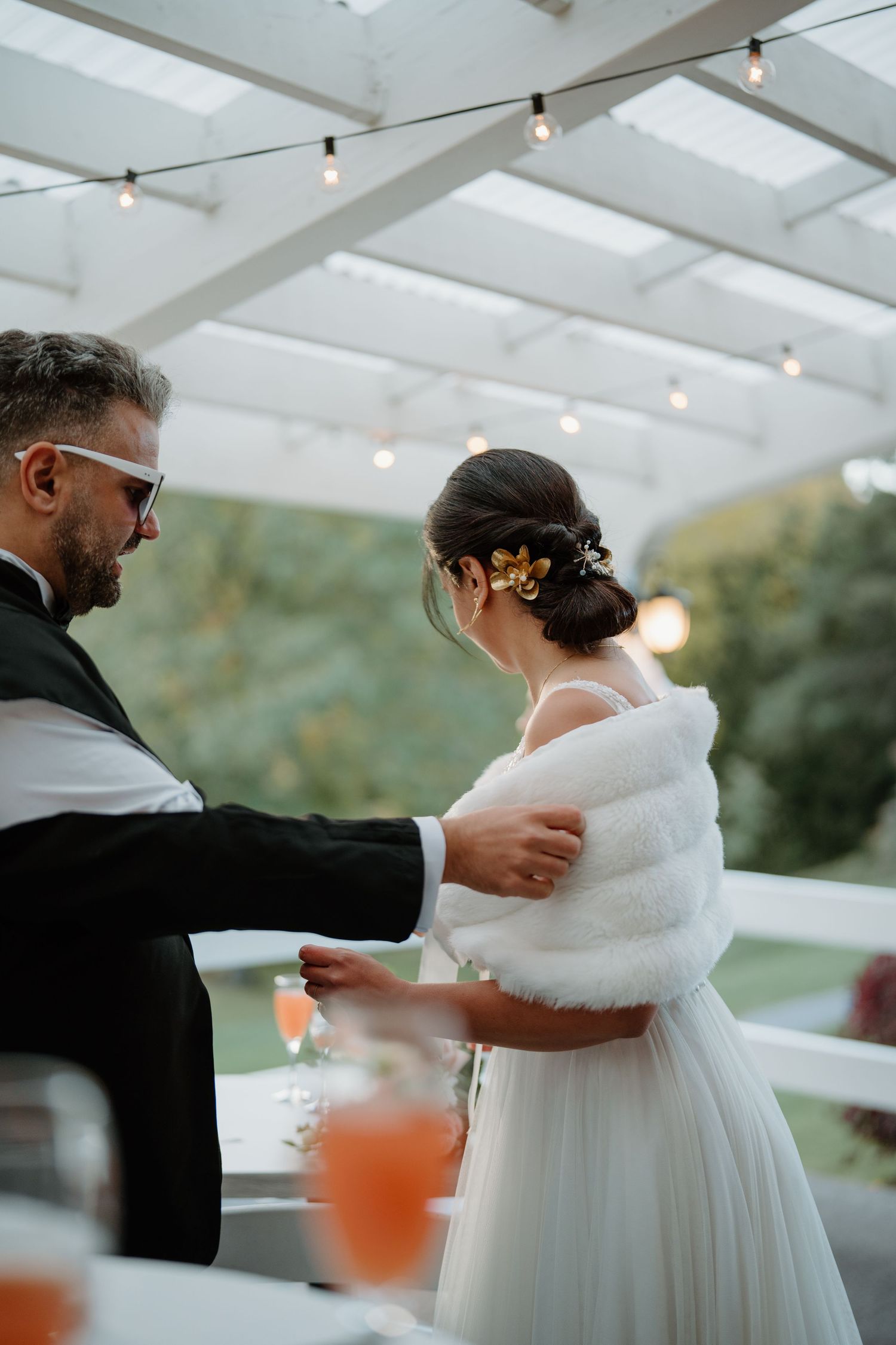 A couple shares a dance under string lights at an outdoor wedding reception.