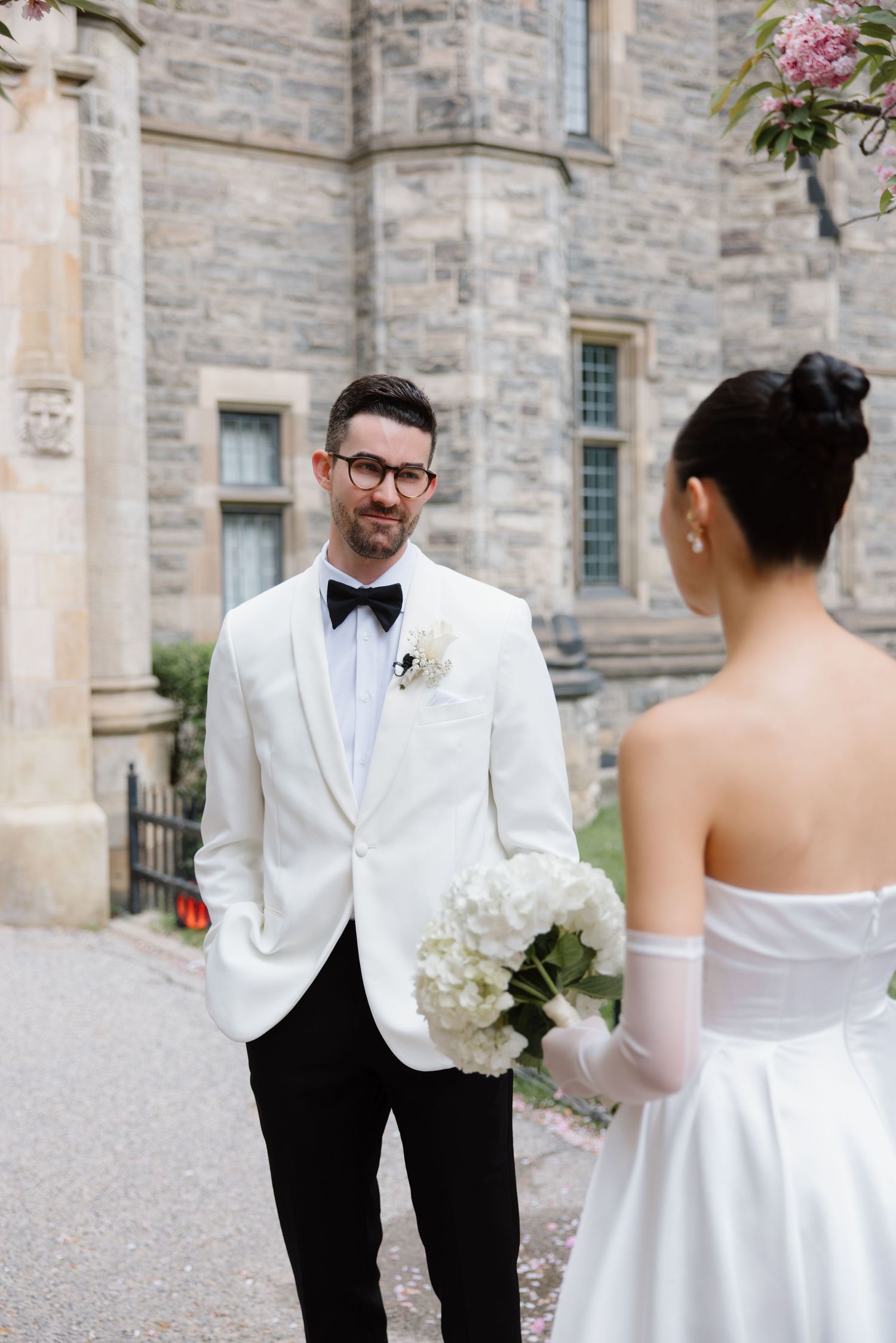 A bride and groom share a tender moment at their wedding outside a stone castle building.