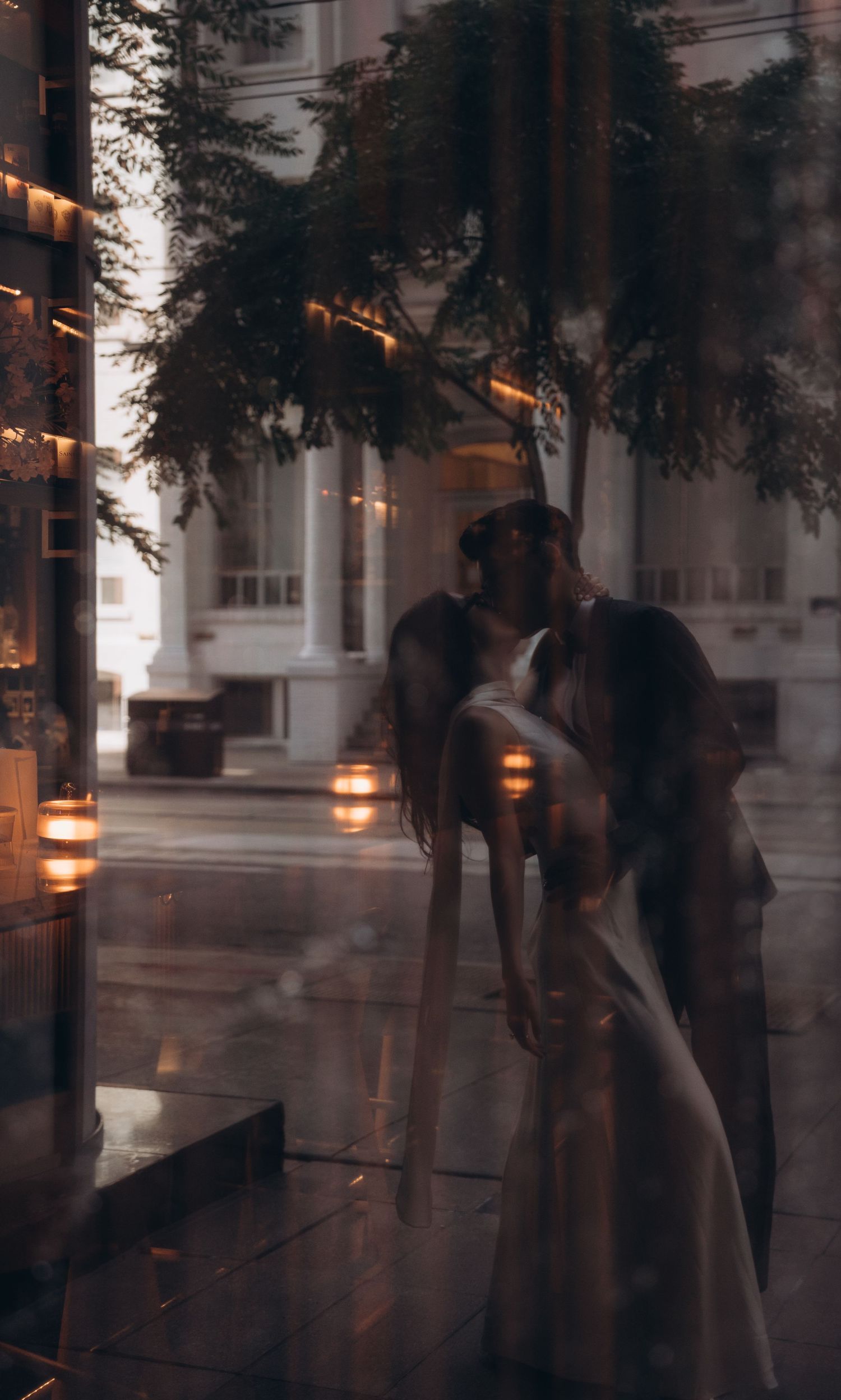 Multiple glass reflections show silhouettes of people dancing and moving under warm lighting in an atmospheric setting.