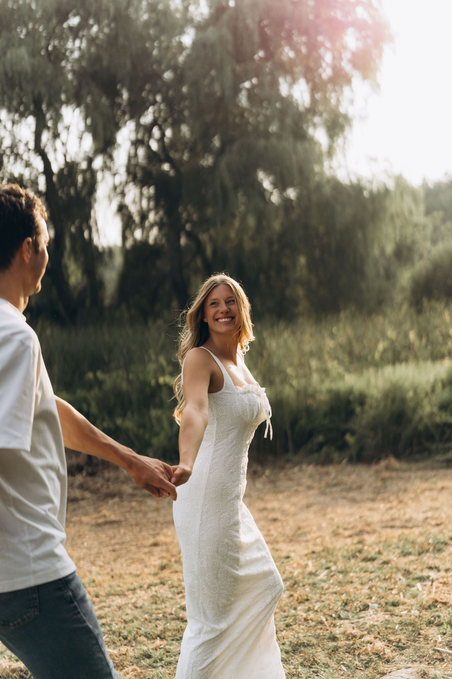 A couple in white and casual attire share a joyful dance together in a sunlit outdoor setting, Toronto suburbs by AZ Photo Studio.