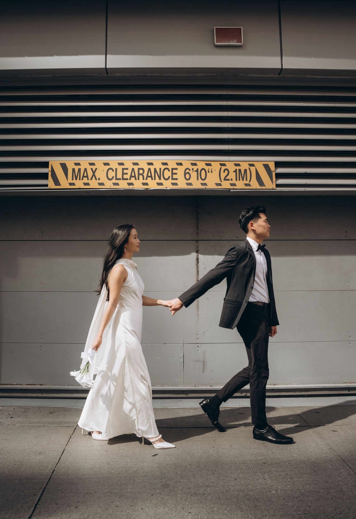 Artistic wedding photo series showing couple walking through parking garage with max clearance sign at 6'10