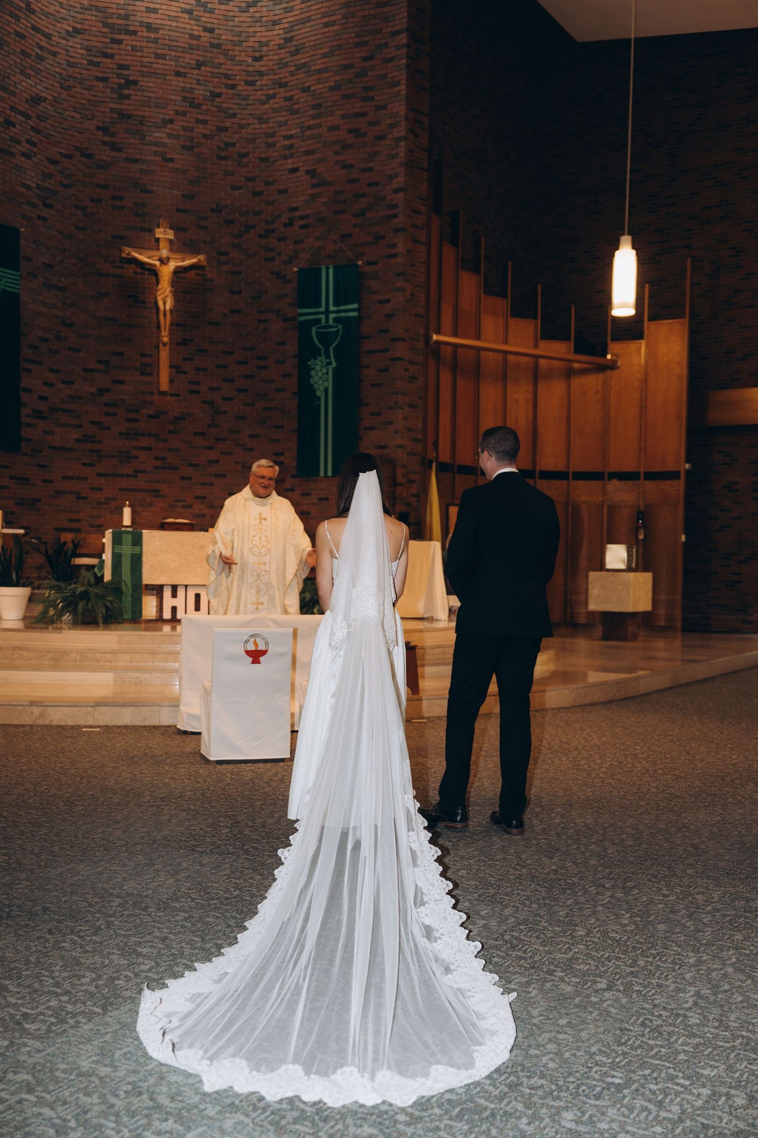 A traditional church wedding ceremony with decorative brick walls and a long flowing white bridal train on display.