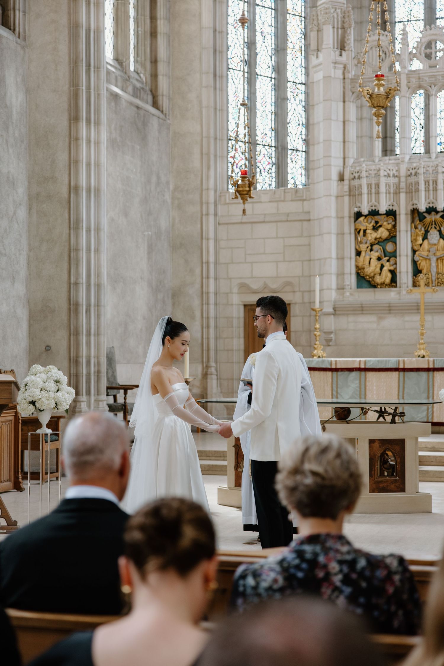 A wedding ceremony taking place in a grand cathedral with ornate architecture and stained glass windows.