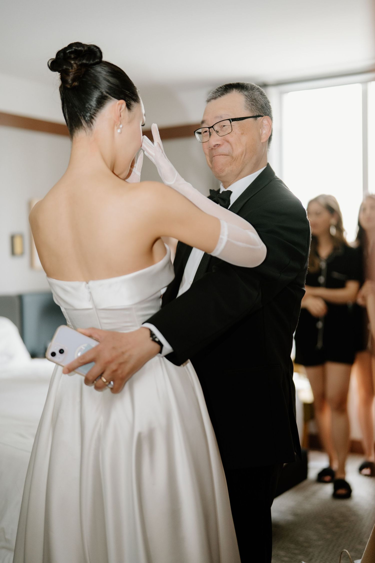 A tender moment at a wedding as a bride in a white strapless gown dances with an older man in a dark suit.