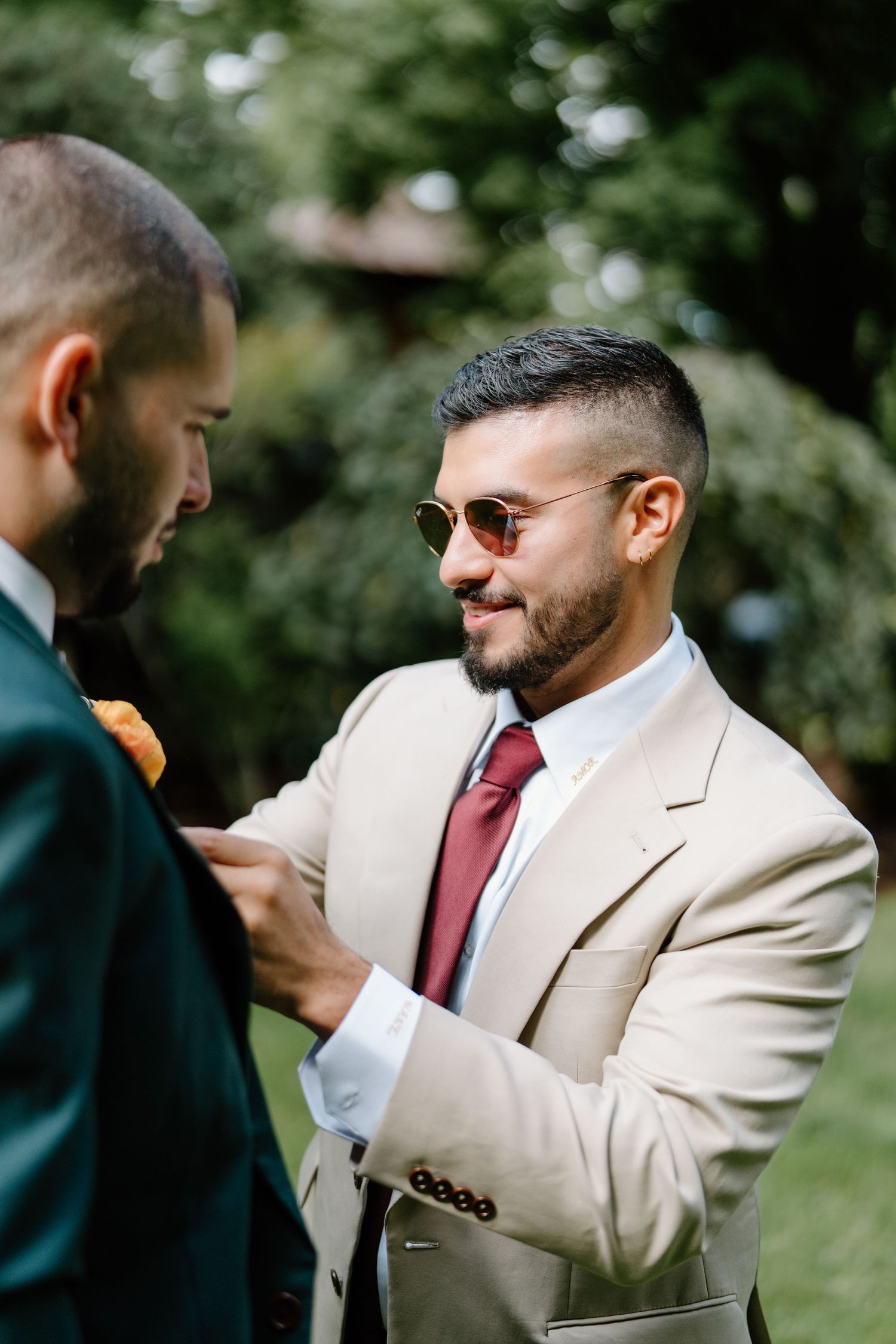 A series of candid moments between two people in contrasting suits against a natural outdoor setting.