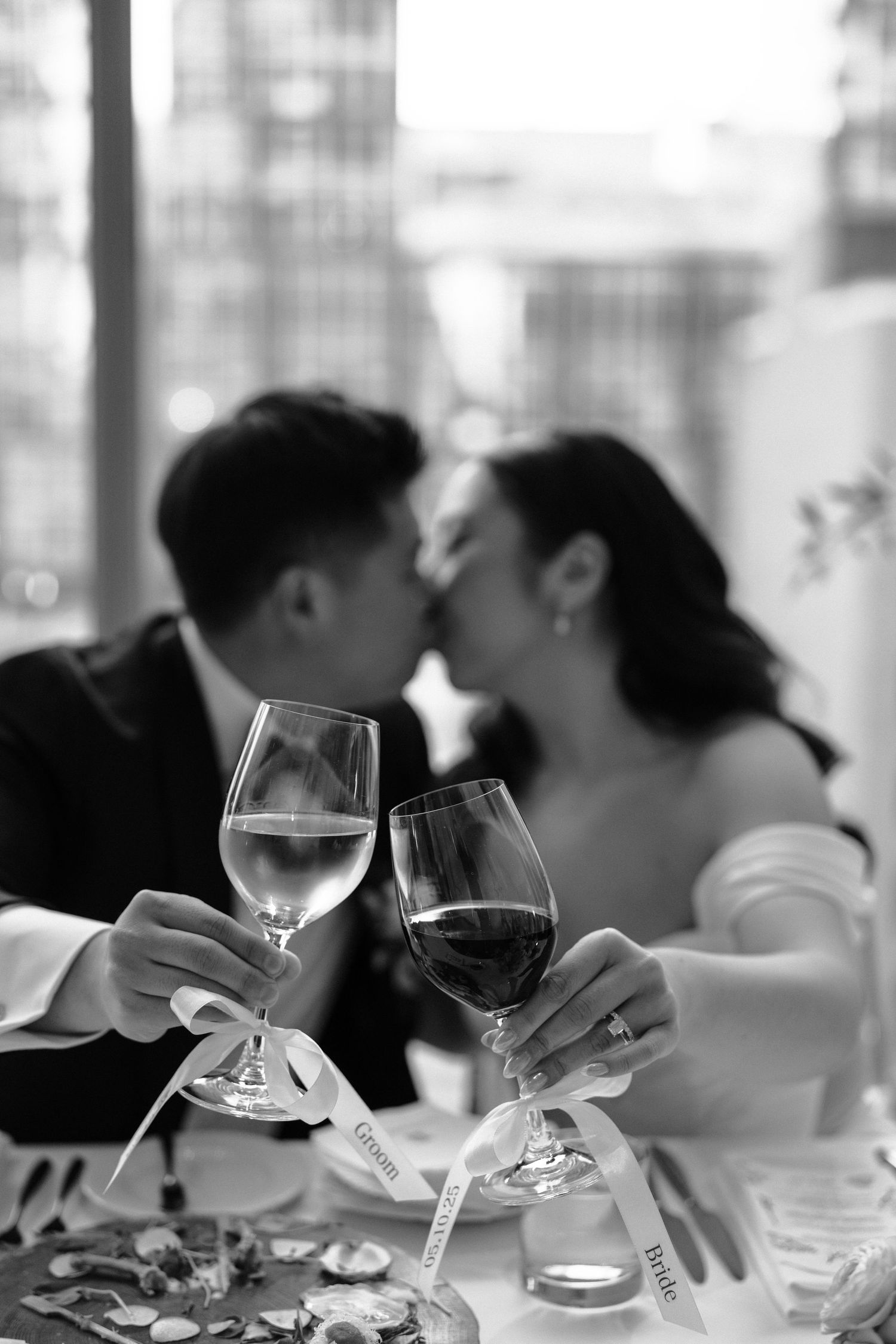 A romantic toast with wine glasses in black and white while sharing an intimate moment at a restaurant table.