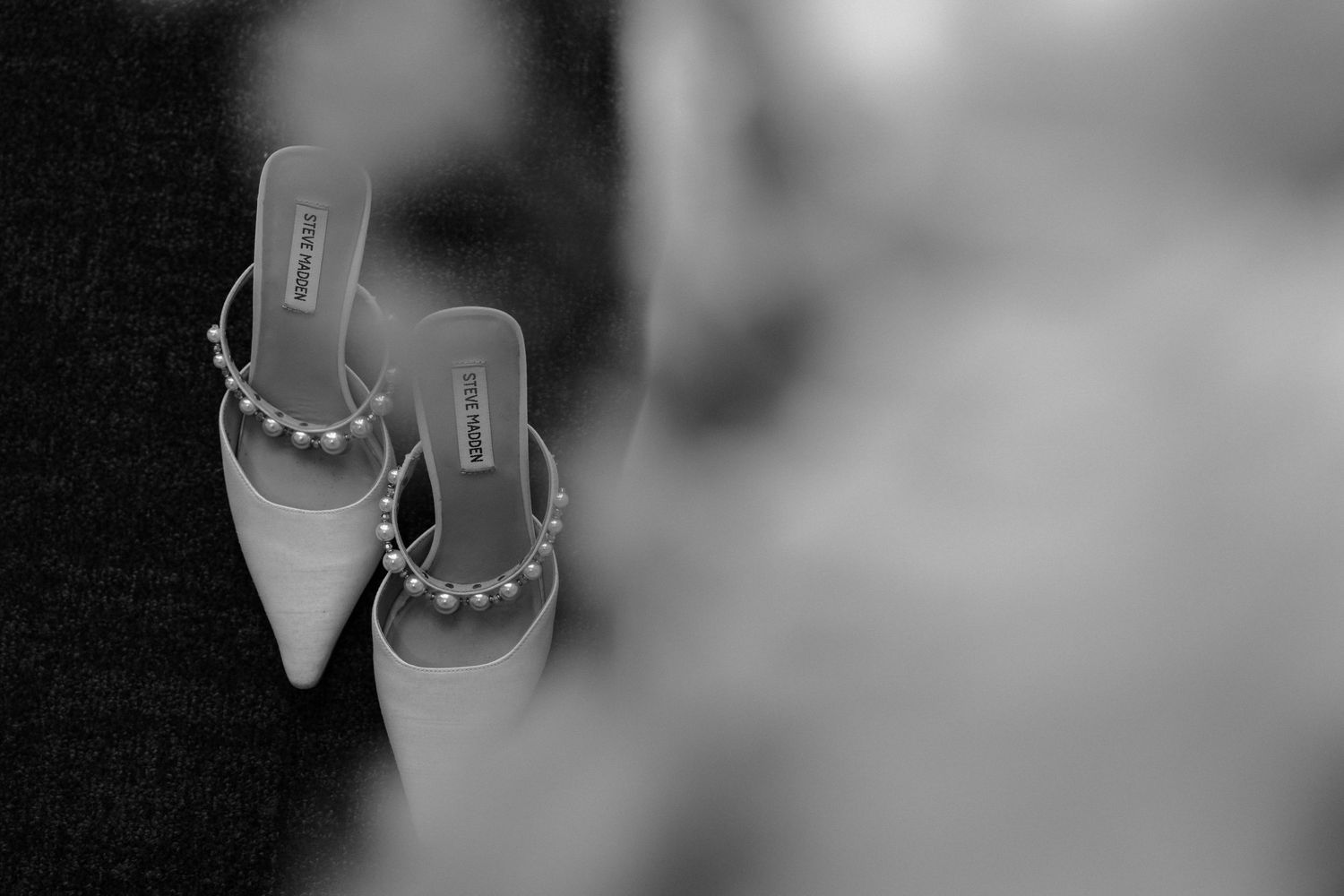 Black and white photo of pointed toe heels with studded straps in a soft focus style.