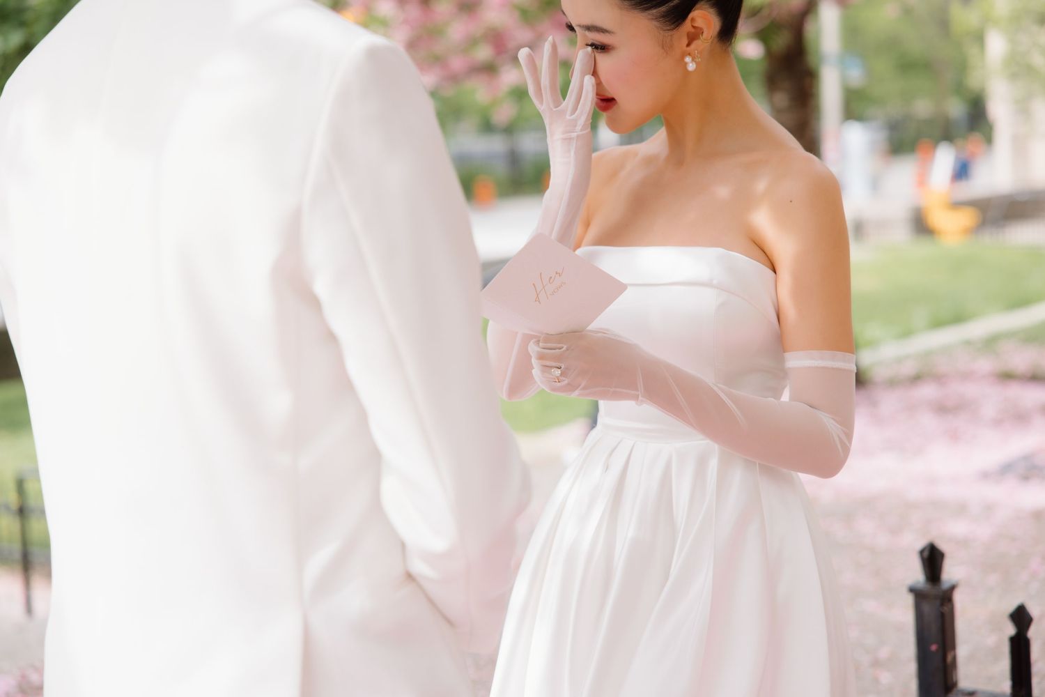 Romantic first look between couple in white wedding attire during outdoor garden ceremony.