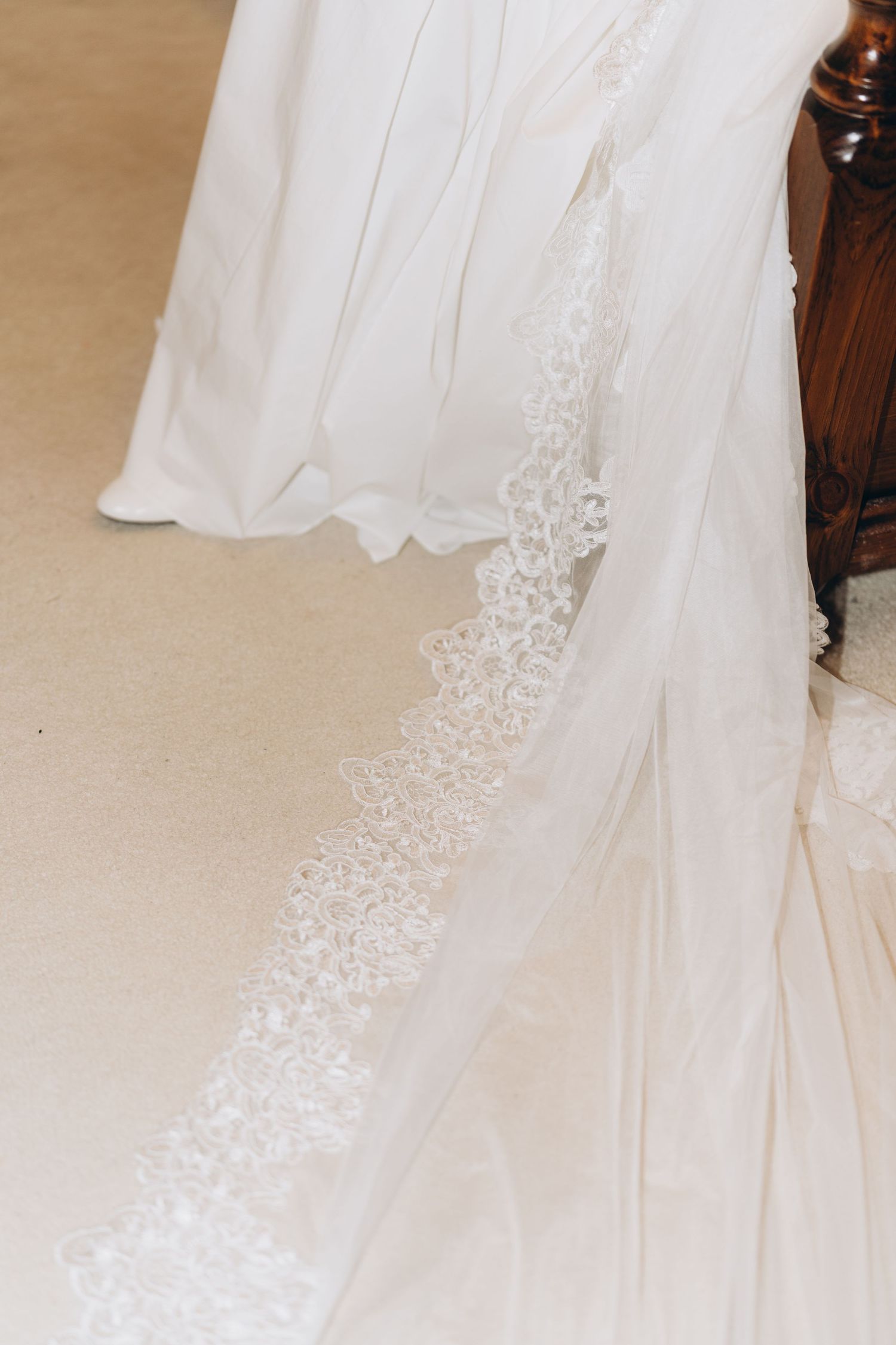 Detailed lace embellishments and delicate beadwork adorn the hem of an elegant white wedding dress.
