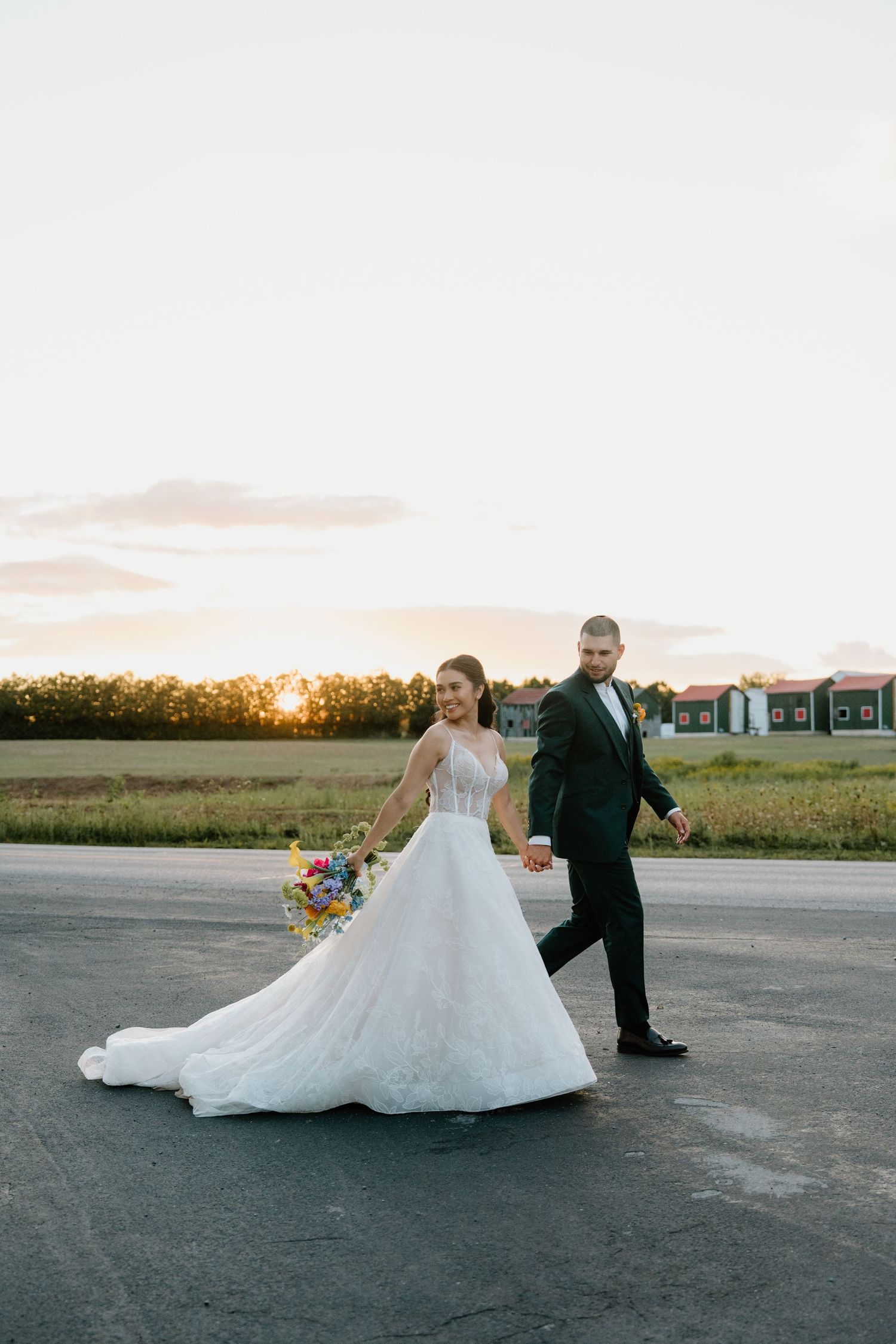 Wedding couple poses dramatically on concrete with sunset light creating elegant silhouettes.