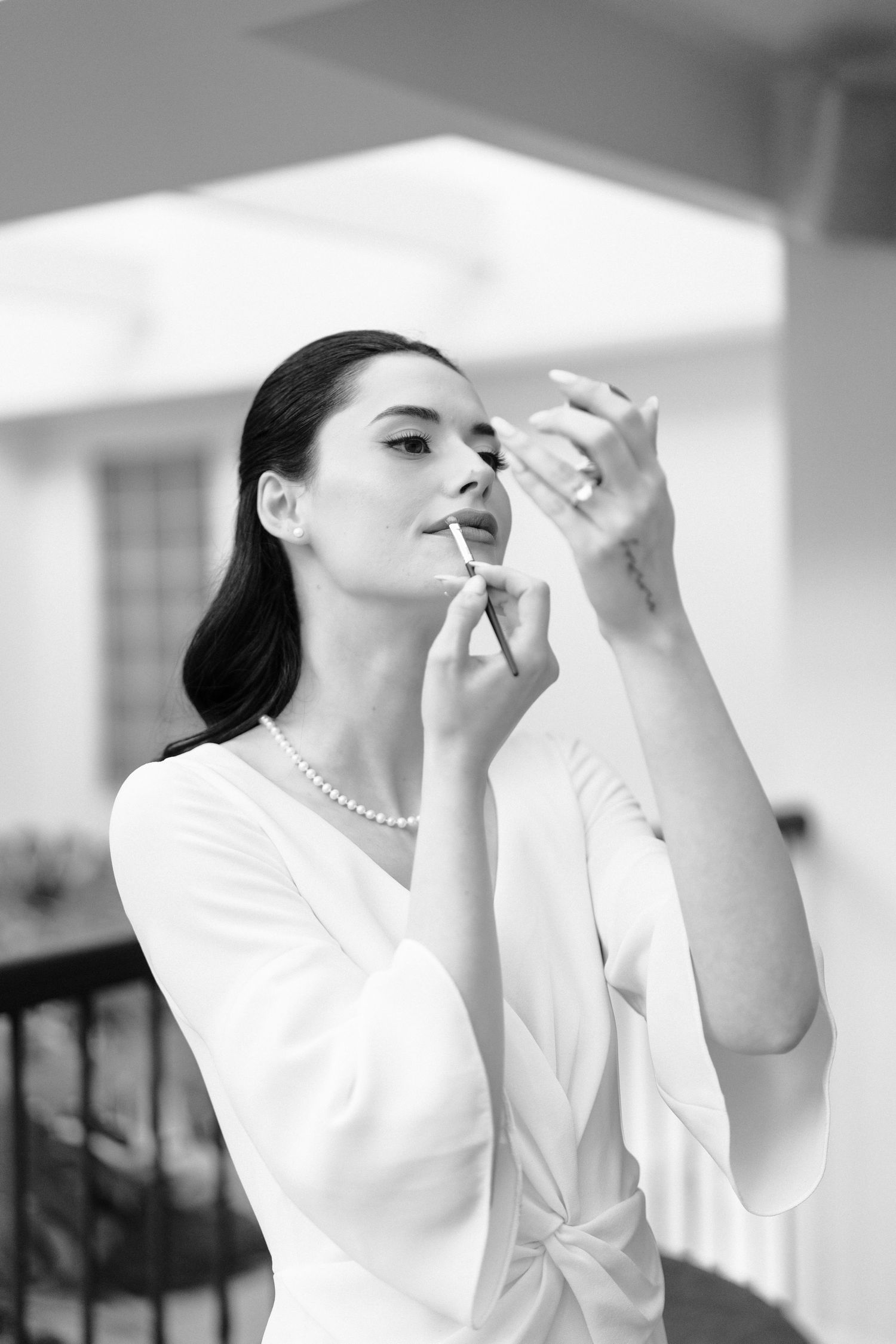 A person in a white blouse applies lipstick in a black and white photo sequence.