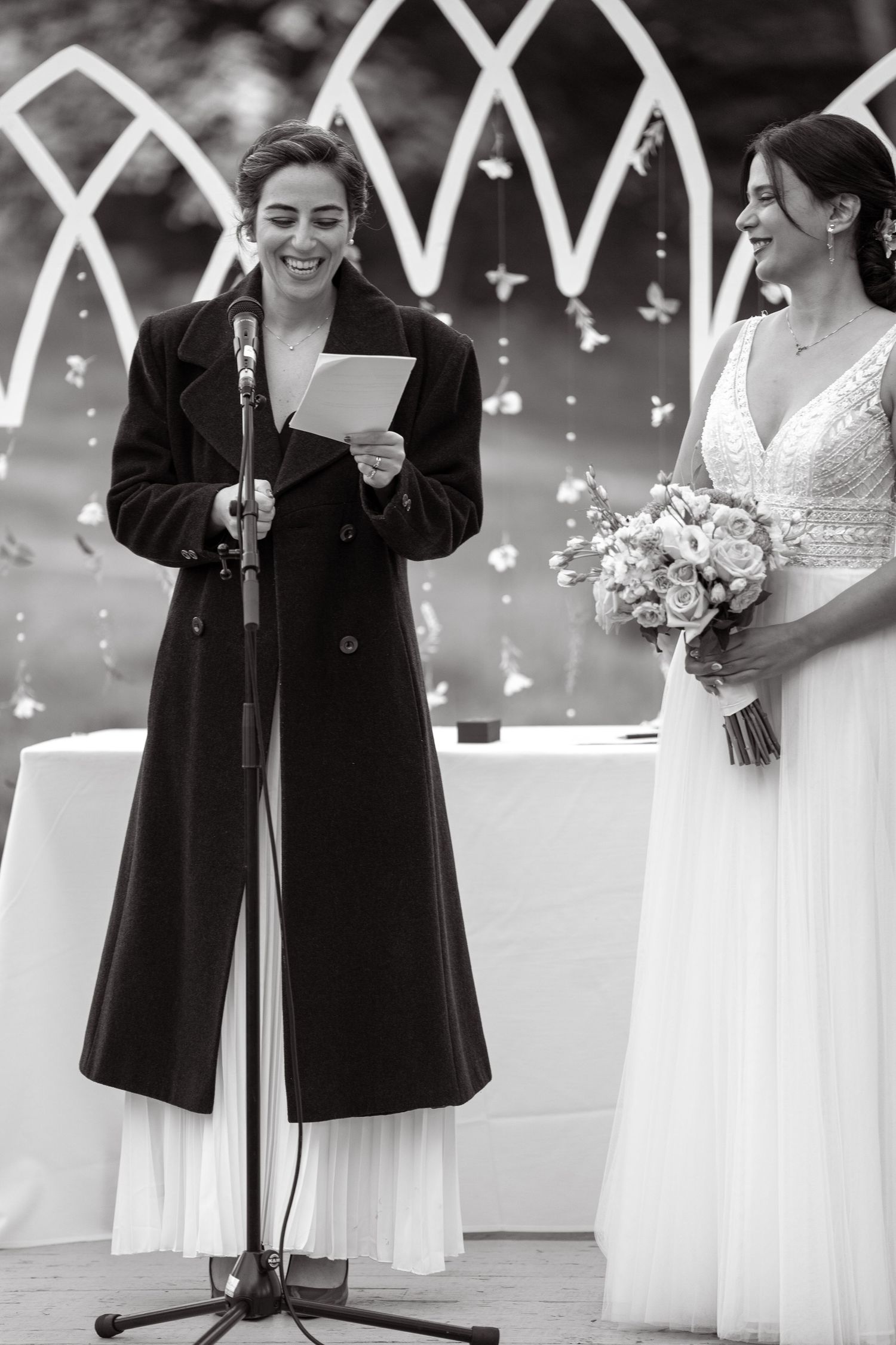 Wedding ceremony with officiant reading from paper at decorated outdoor altar.